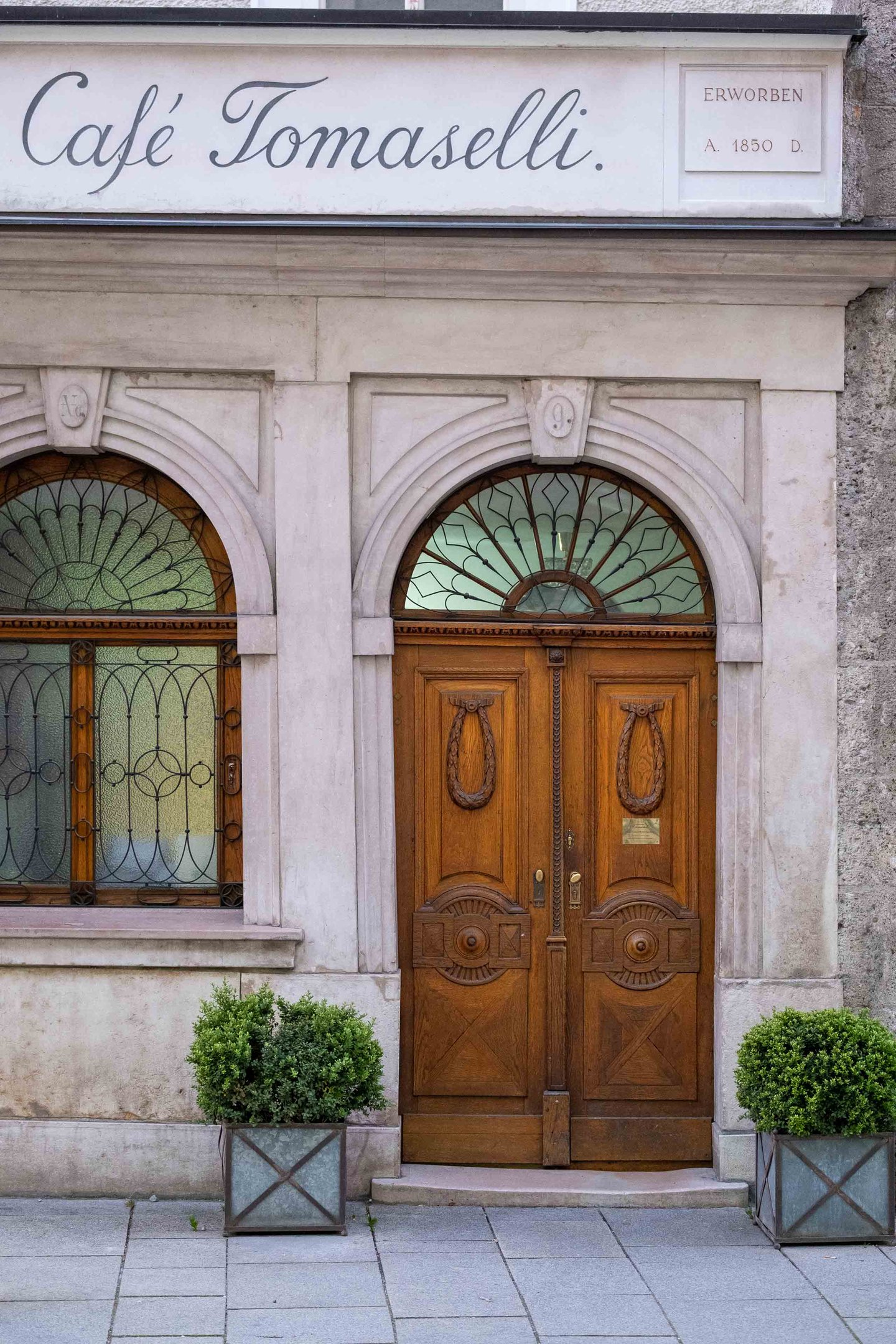 Entrance arch with Cafe Tomaselli signage and wooden doors on Alter Markt in Salzburg
