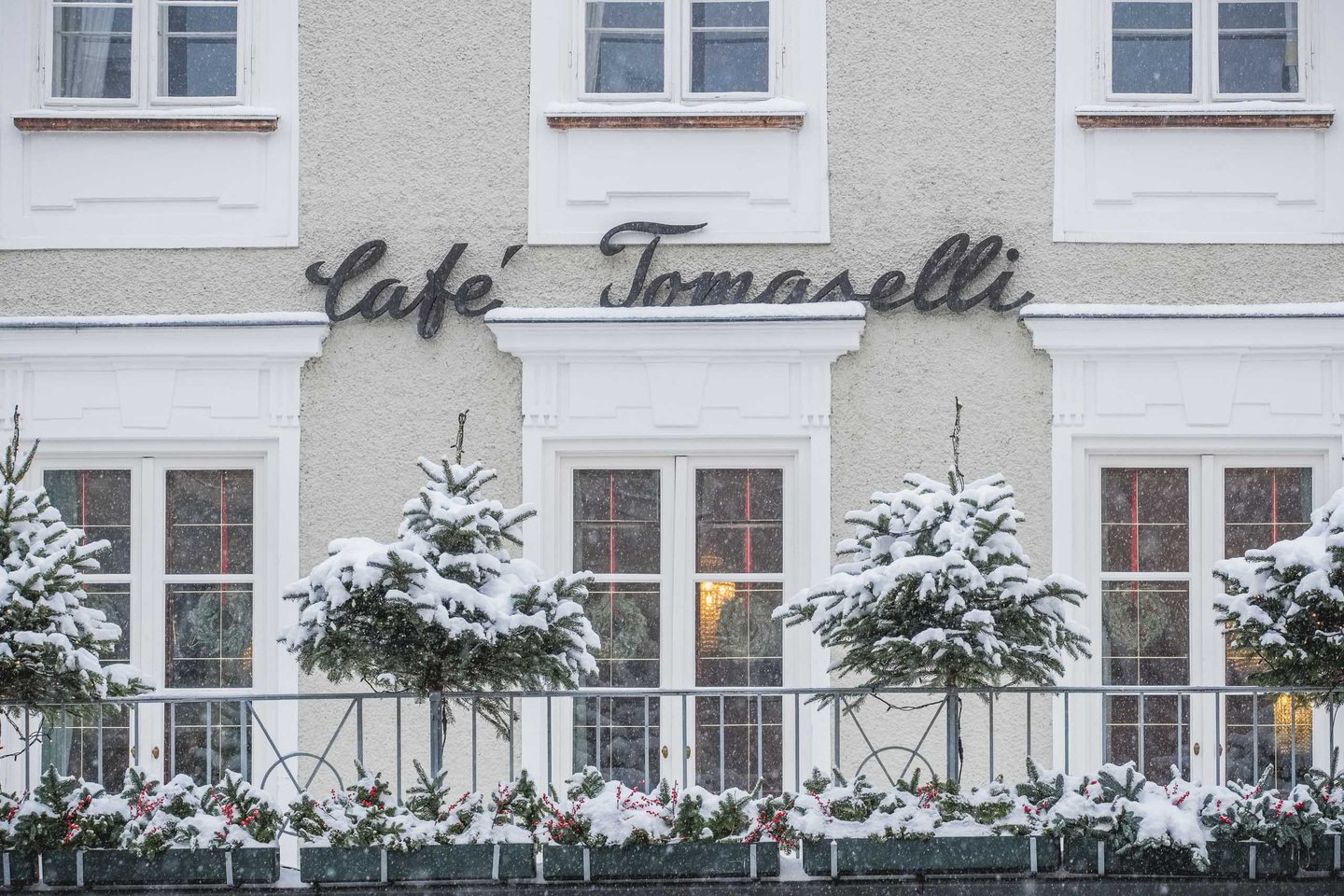 Snow covered trees and window boxes in front of the Cafe Tomaselli facade in Salzburg.