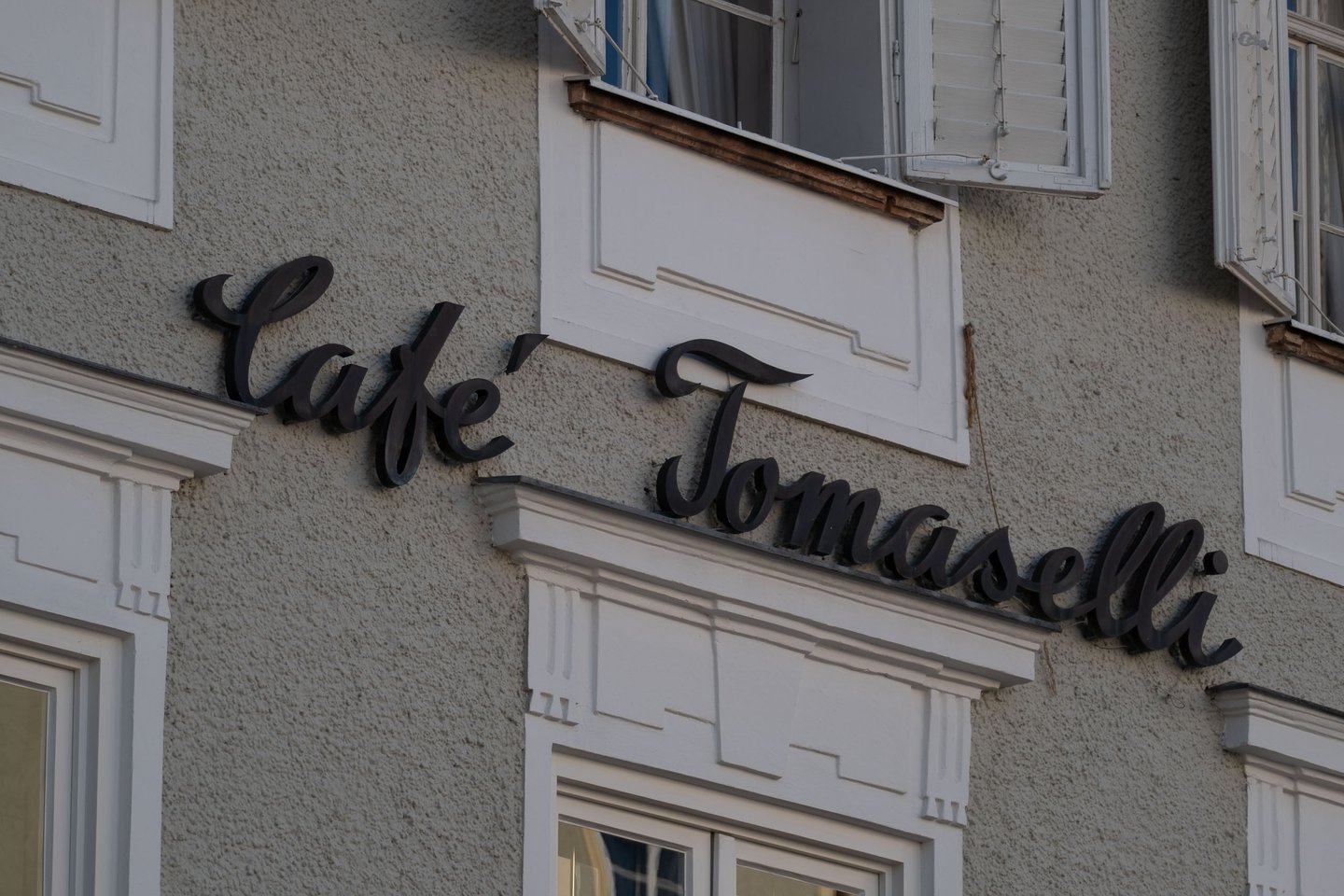 Café Tomaselli script signage mounted on its historic facade in Salzburg old town.