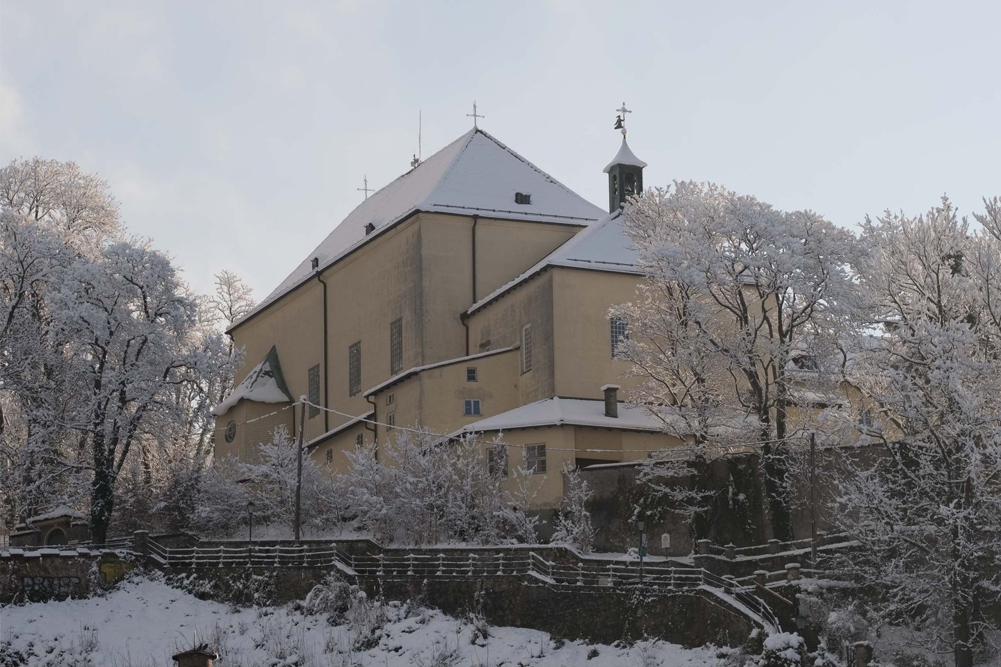 Capuchin monastery church on a snowy forested hillside above Salzburg.