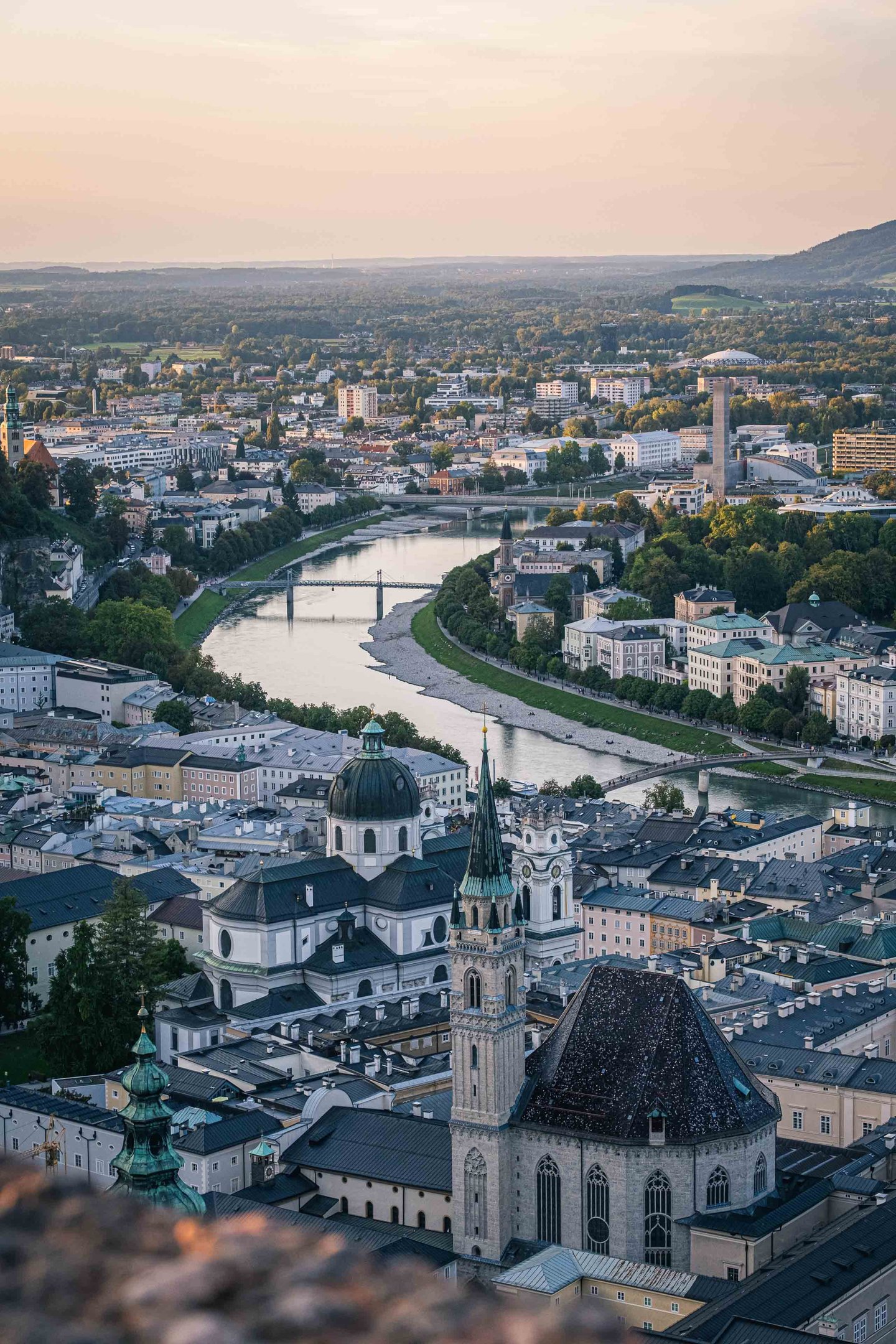 Christuskirche and Kollegienkirche domes above Salzburg Altstadt with Salzach river at sunset