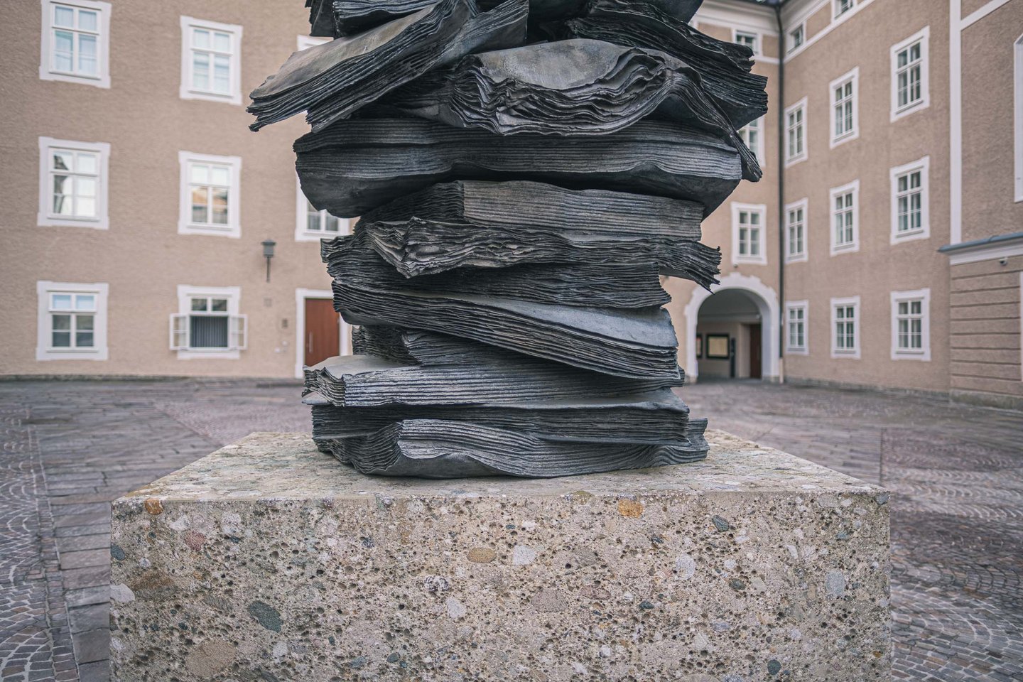 Stacked bronze books of Anselm Kiefer Die Sprache der Voegel sculpture in the Toscaninihof area in Salzburg.