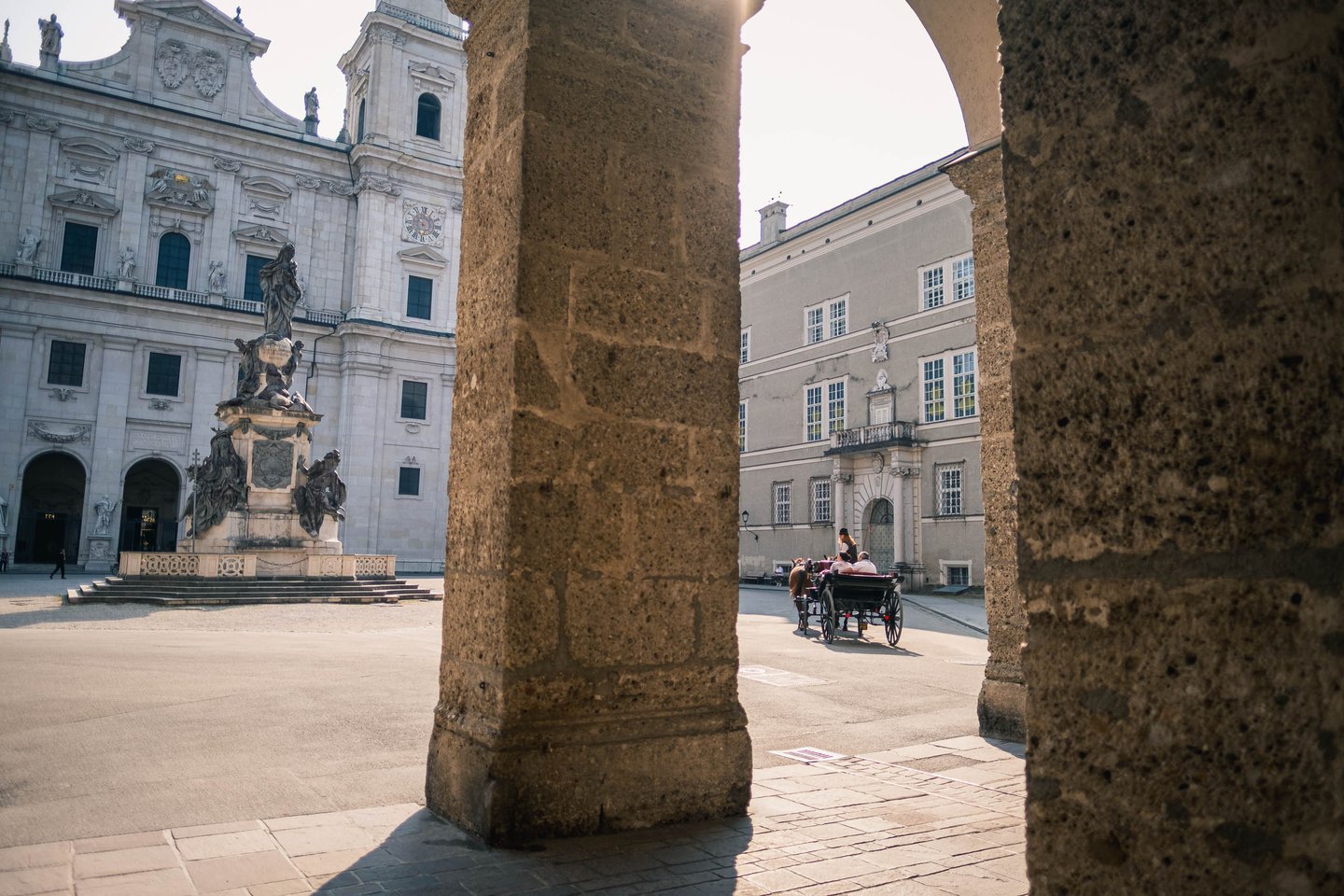 Mariensaule column on Domplatz seen through Residenzplatz archway with fiaker carriage in Salzburg