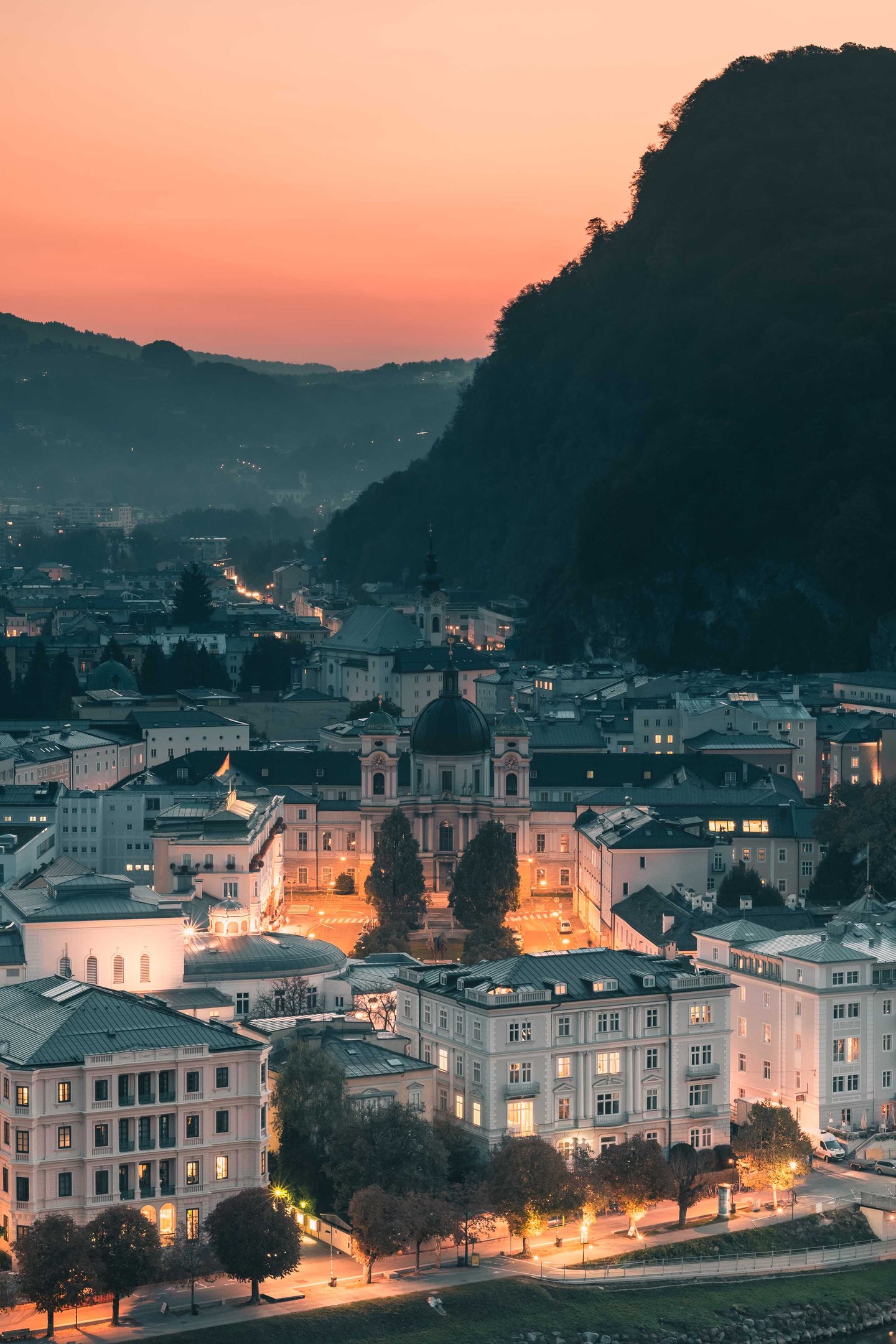 Dreifaltigkeitskirche illuminated at dusk with Mönchsberg rising behind in Salzburg.