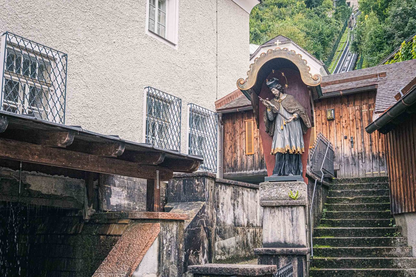 Small painted saint shrine on stone pillar beside the Festungsbahn funicular tracks in Salzburg.