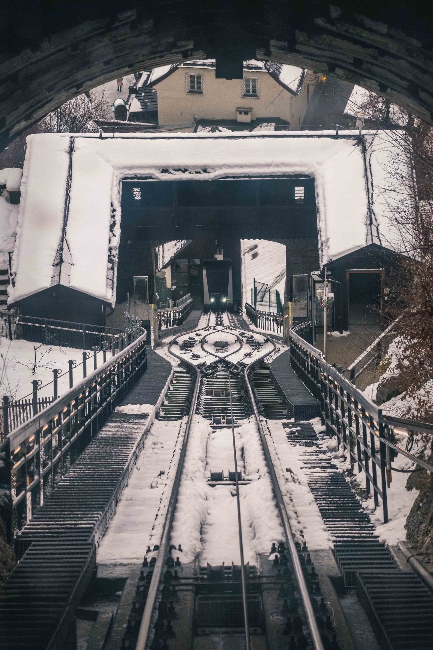 Festungsbahn funicular tracks descend from Hohensalzburg between snowy stone walls in Salzburg.