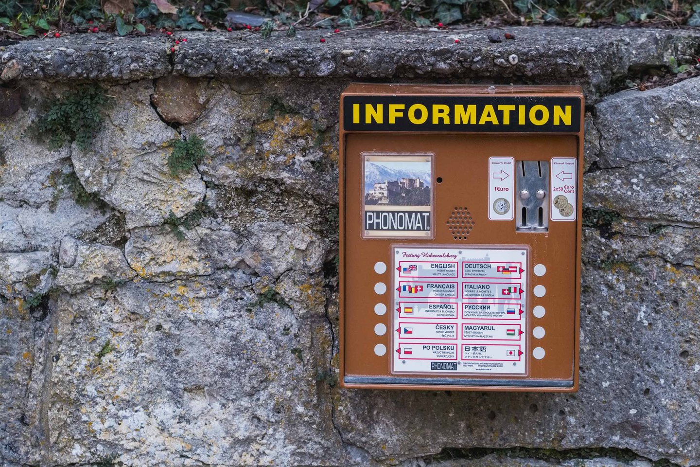 Multilingual Phonomat audio information box mounted on a stone wall on the path up to Hohensalzburg Fortress.