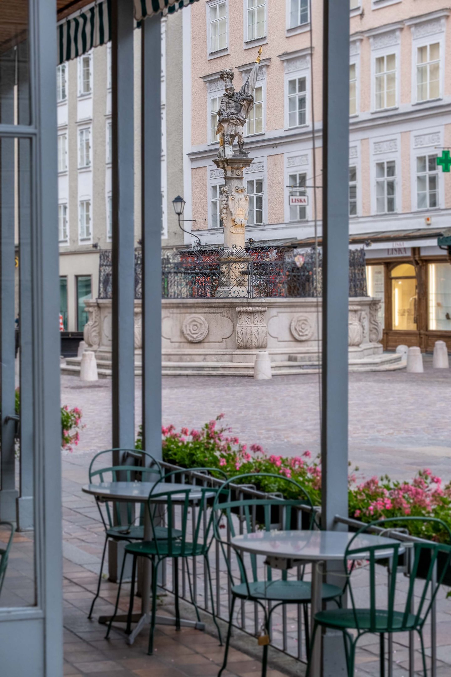 Florianibrunnen fountain on Alter Markt viewed through Cafe Tomaselli terrace windows in Salzburg