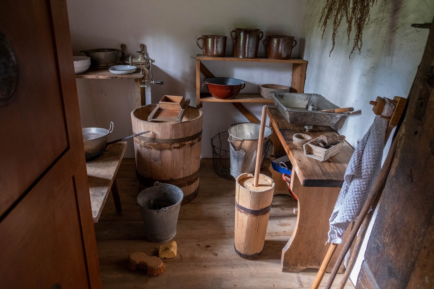 Traditional dairy workroom with wooden butter churns and copper pots at an open-air museum near Salzburg.