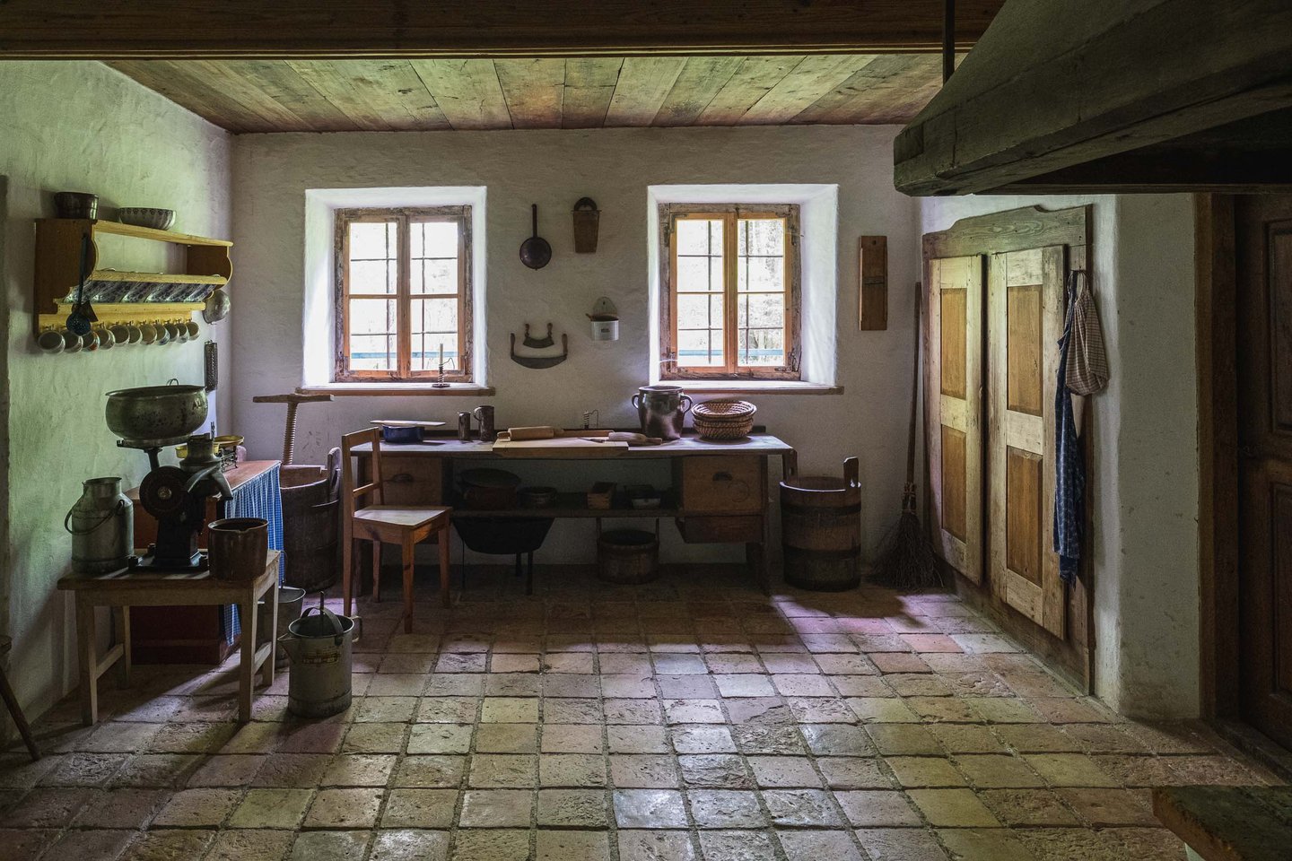 Rustic farmhouse kitchen interior with wooden table chair and stone floor at an open-air museum near Salzburg.