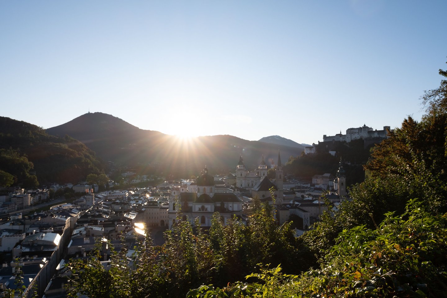 Sun rising over the Gaisberg with Hohensalzburg Fortress and Salzburg Altstadt silhouetted in the foreground