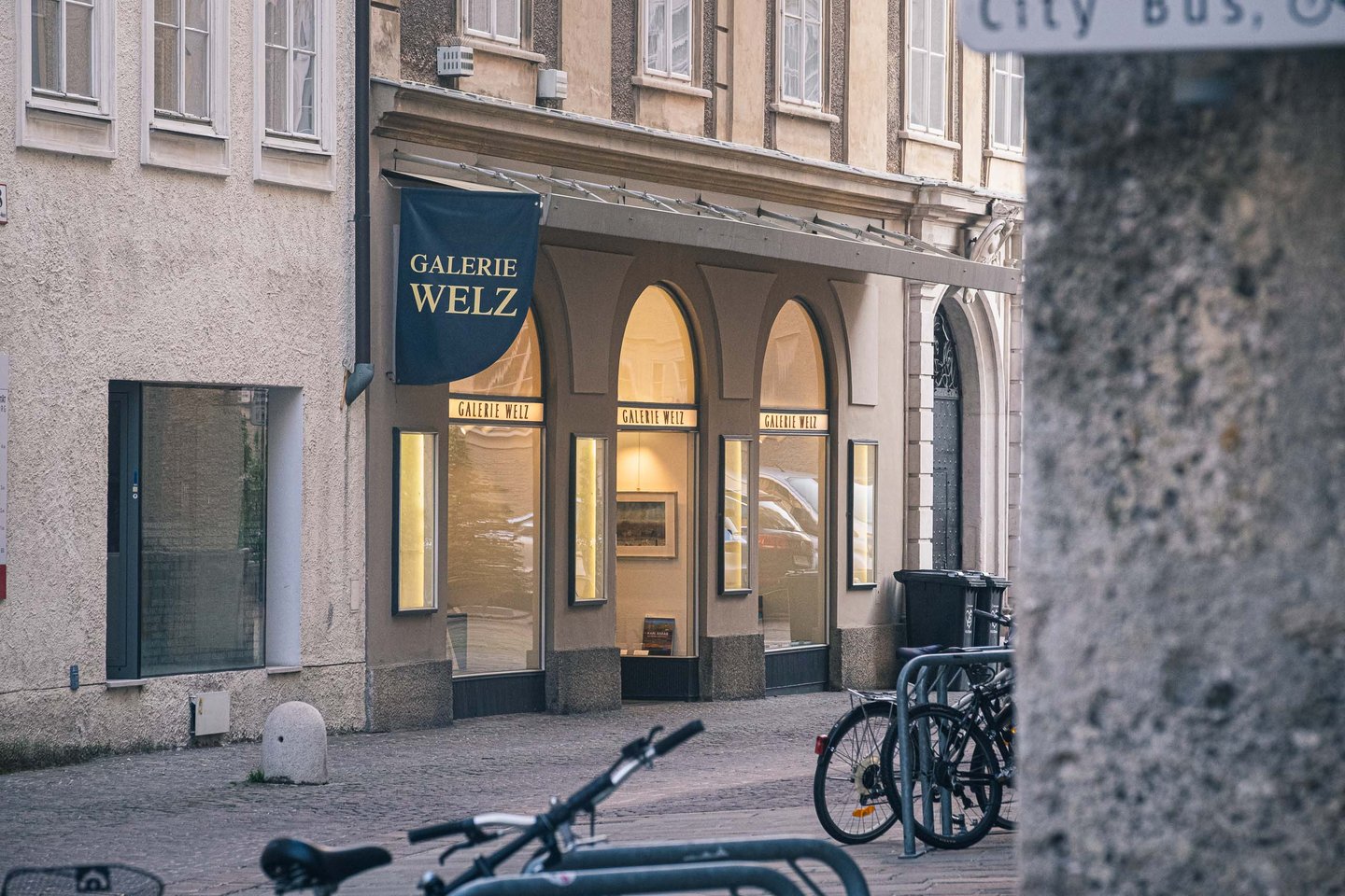 Storefront of Galerie Welz art gallery with arched windows on Sigmund Haffner Gasse in Salzburg old town.