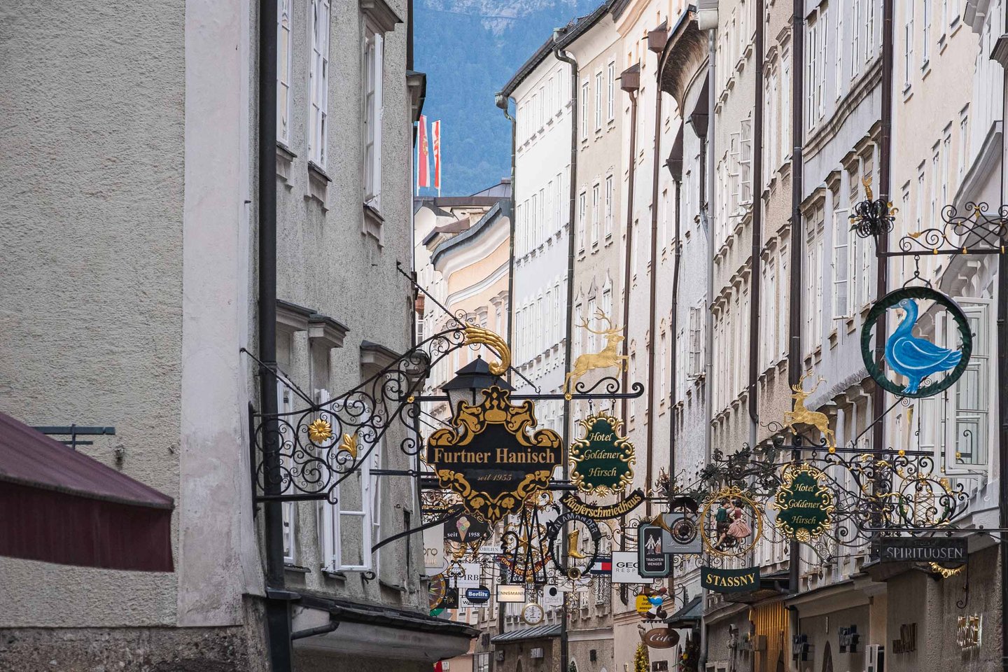Cluster of gilded wrought iron shop signs along narrow Getreidegasse in Salzburg old town