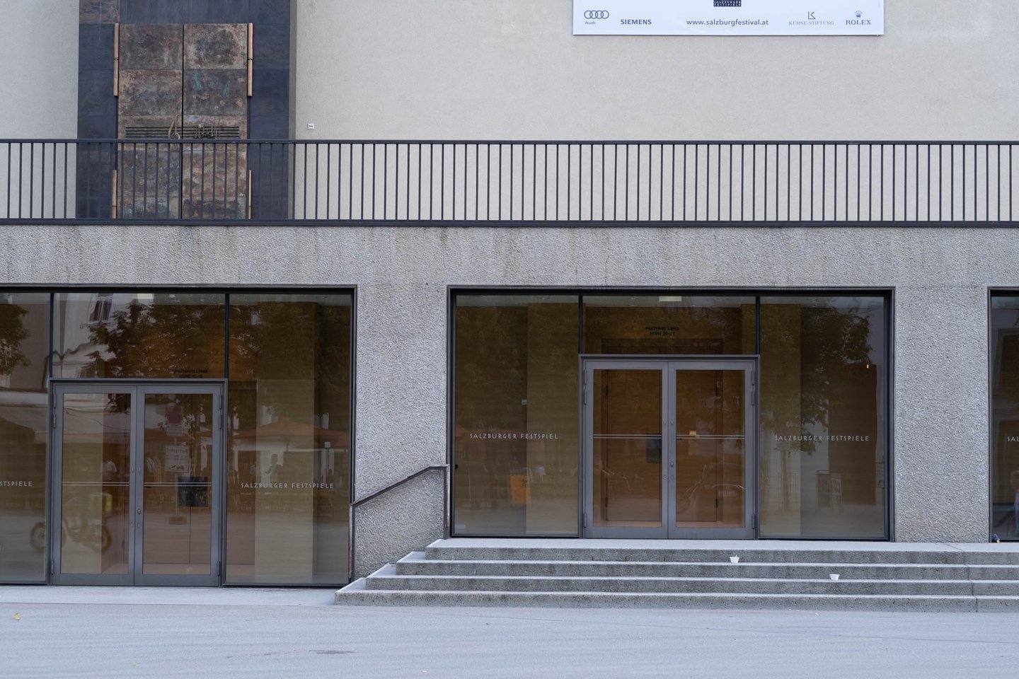 Glass entrance doors of the Grosses Festspielhaus with Salzburger Festspiele lettering in Salzburg old town.
