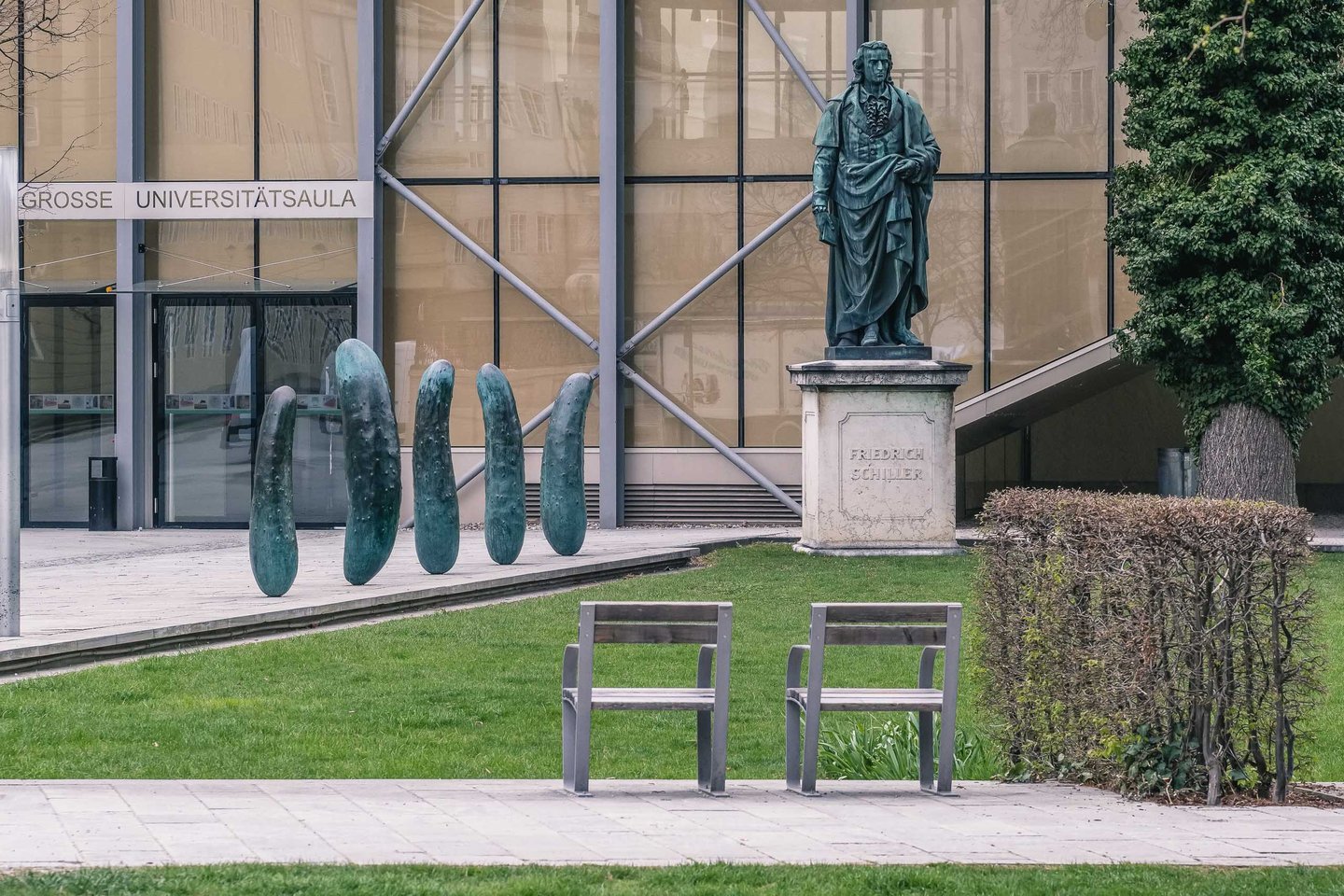 Erwin Wurm Gurken bronze pickle sculptures beside the Friedrich Schiller statue at Grosse Universitaetsaula in Salzburg