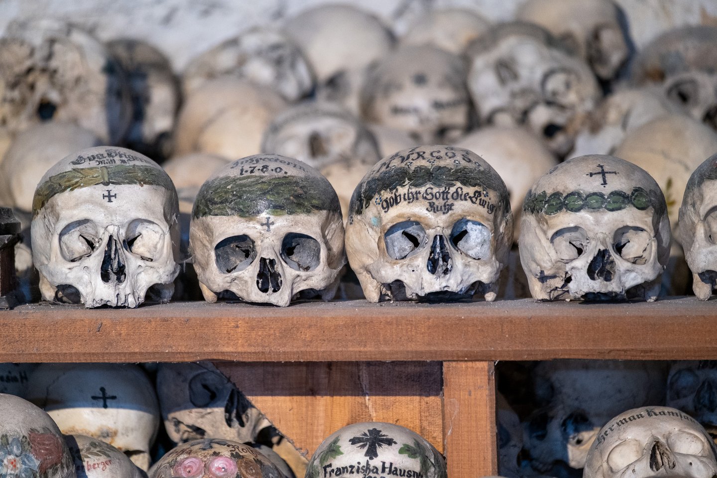Four of the oldest skulls in the charnel house sit in a row, their crowns painted with broad green laurel bands, one dated 1780 and another inscribed Gob ihr Gott die ewige Ruhe.
