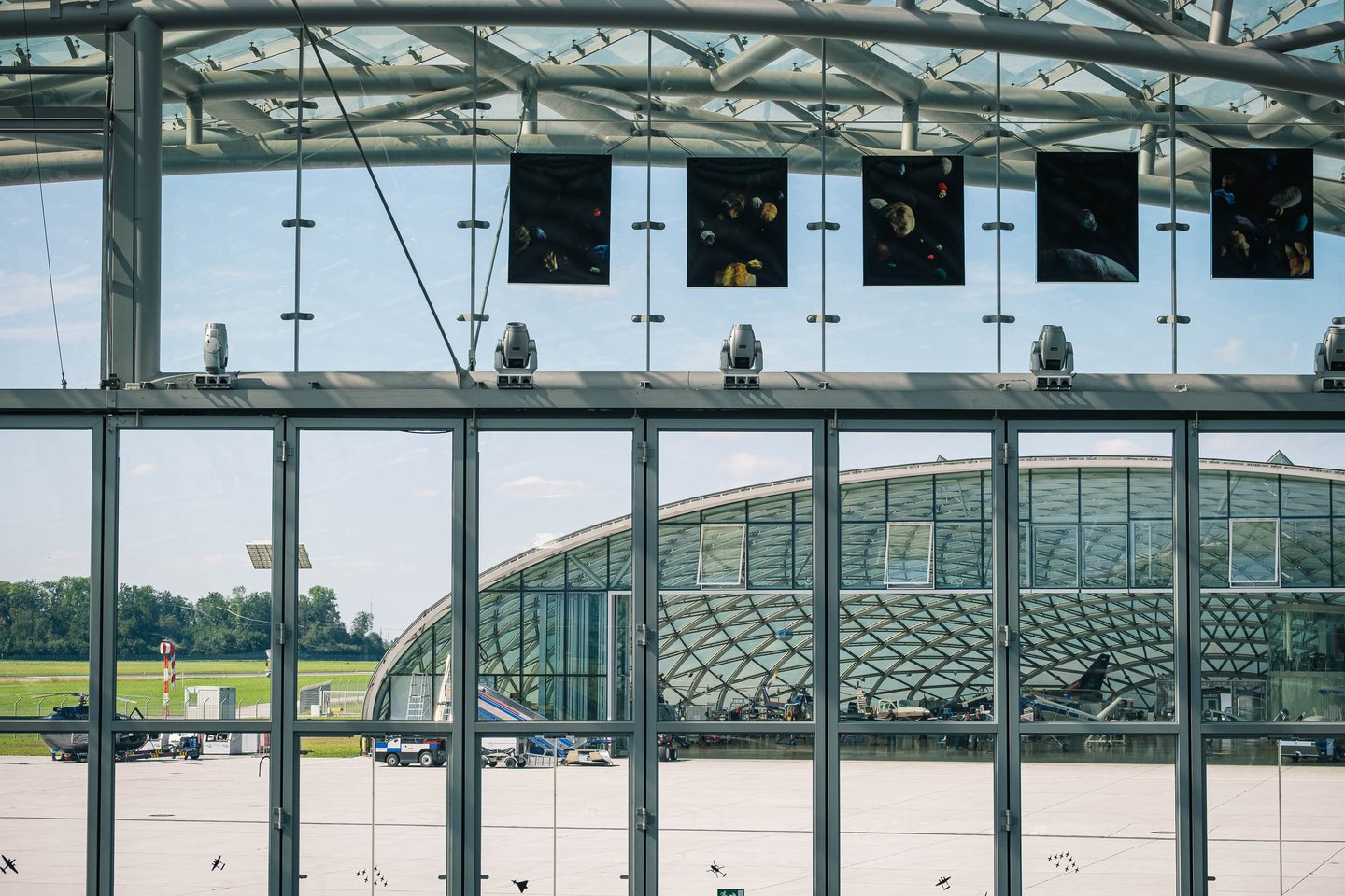 The Hangar-7 glass dome seen through a window with aircraft parked on the tarmac in Salzburg.