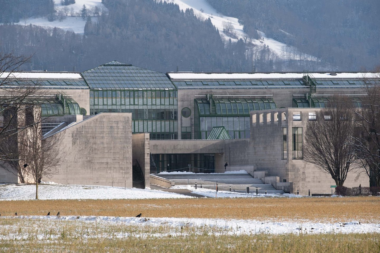 Glass and steel hangar architecture of Hangar-7 with snow-dusted hills behind in Salzburg.