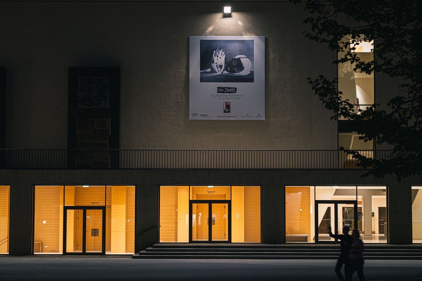 Illuminated Haus fuer Mozart facade at night with 100 Jahre Festspiele poster in Salzburg old town