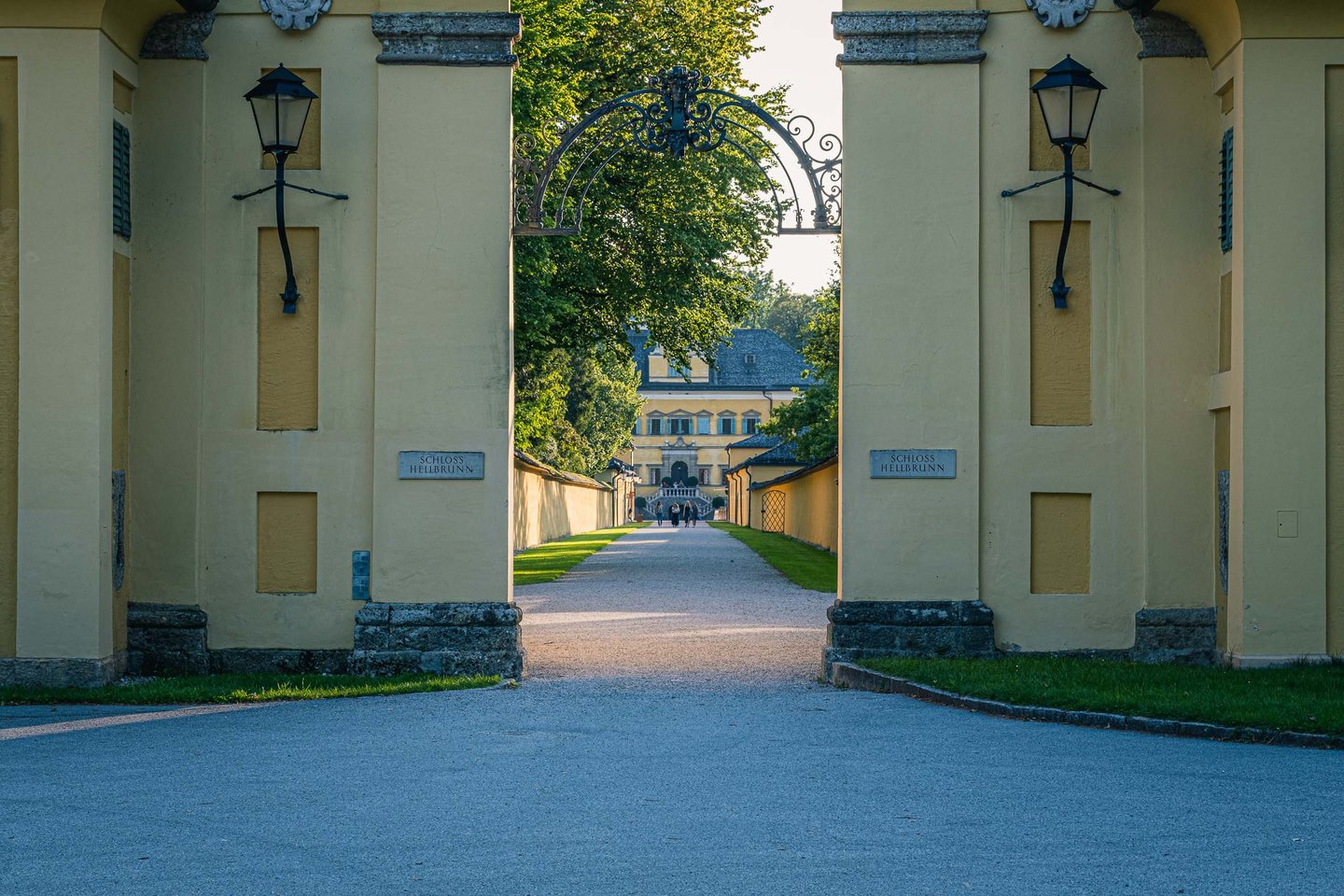 View through the Schloss Hellbrunn entrance gate toward the yellow palace in Salzburg.