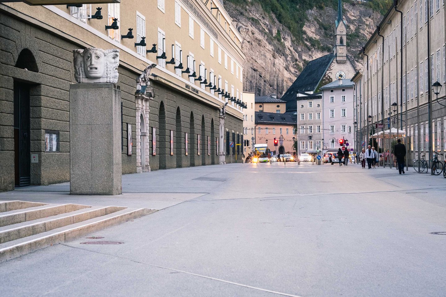 Hofstallgasse with Festspielhaus colonnade and Moenchsberg cliff face in Salzburg old town.