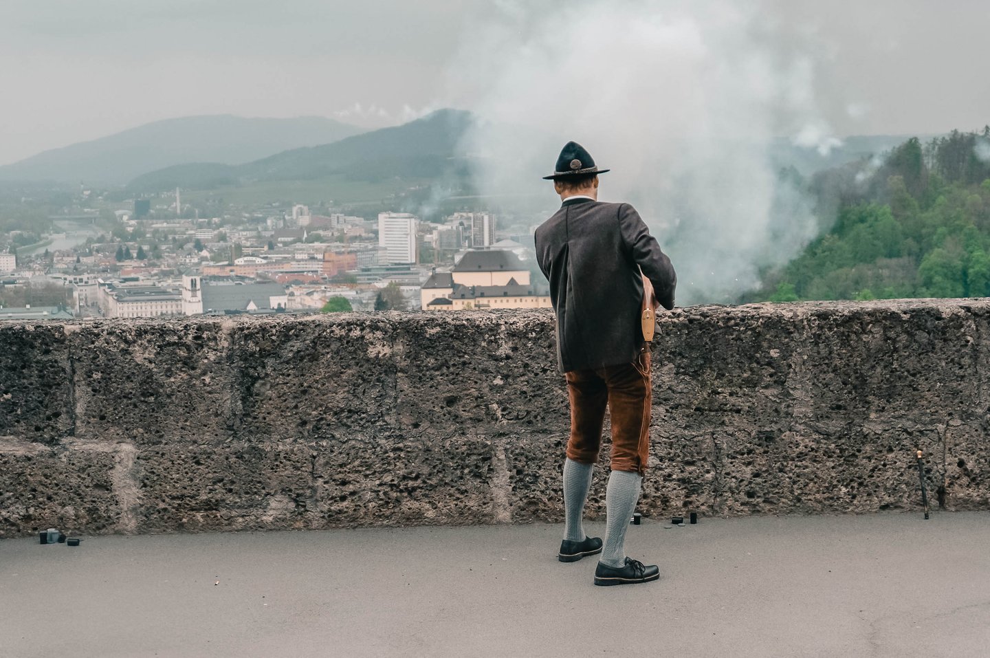 Prangerschuetzen marksman in lederhosen fires a ceremonial handgonne from the fortress rampart in Salzburg