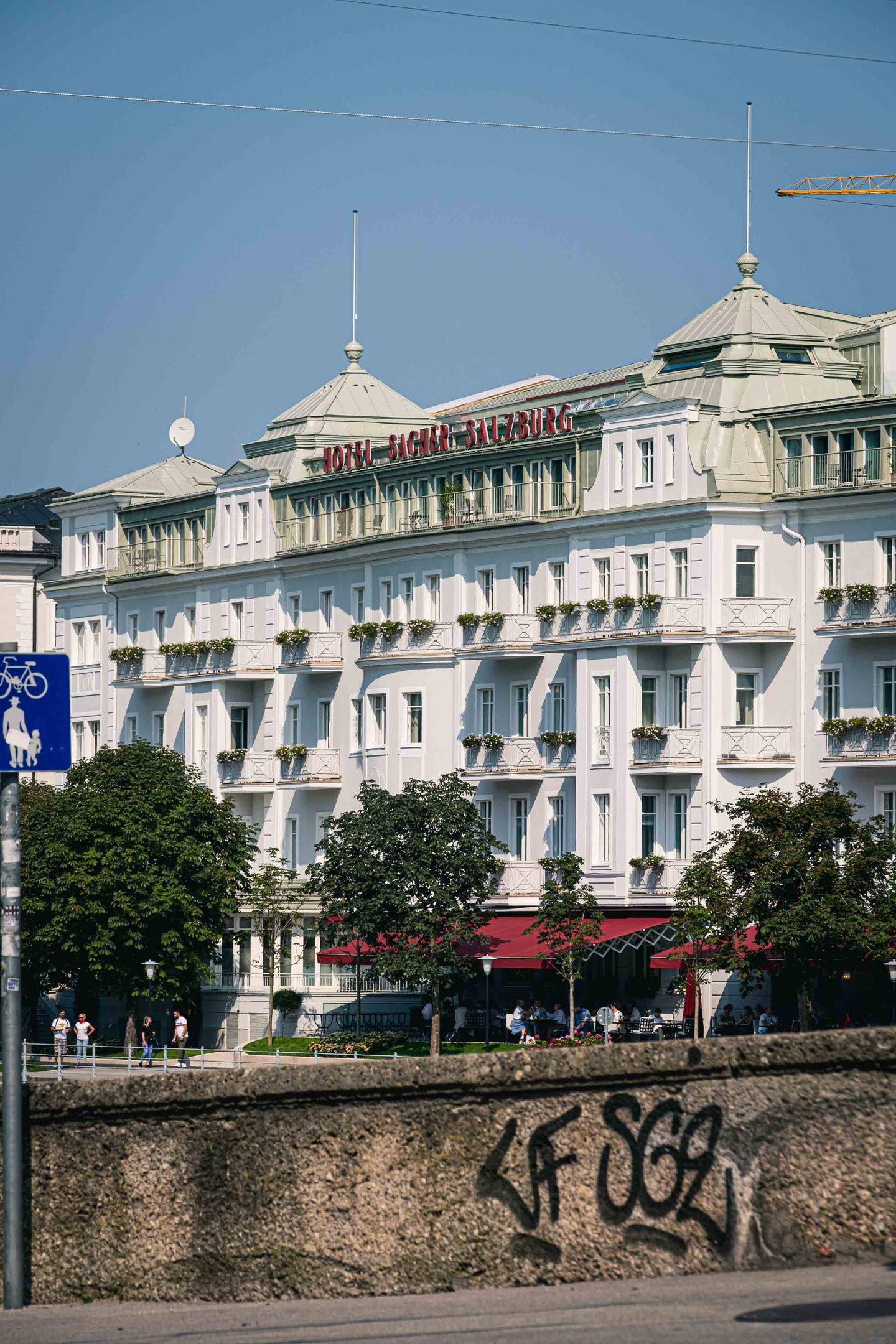Hotel Sacher Salzburg white facade with terrace cafe seen from across the Salzach in Salzburg