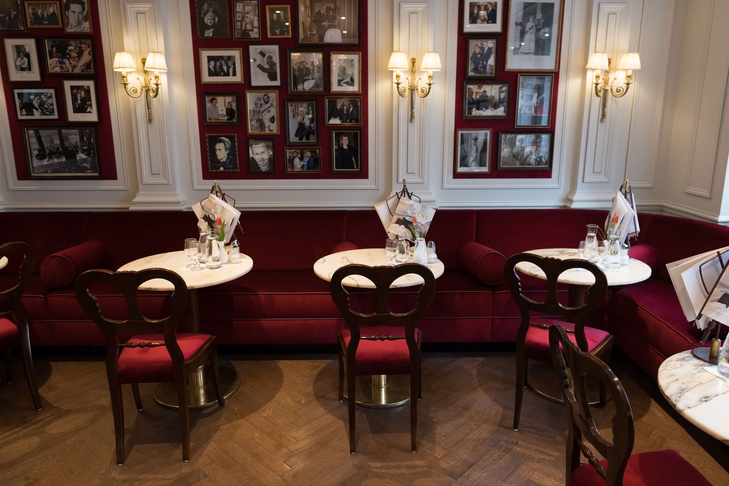 Red banquette seating below festival portrait photographs inside Hotel Sacher Salzburg