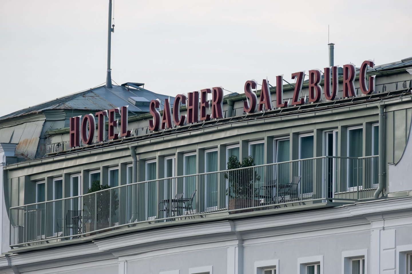 Red Hotel Sacher Salzburg rooftop sign above balcony facade along the Salzach river