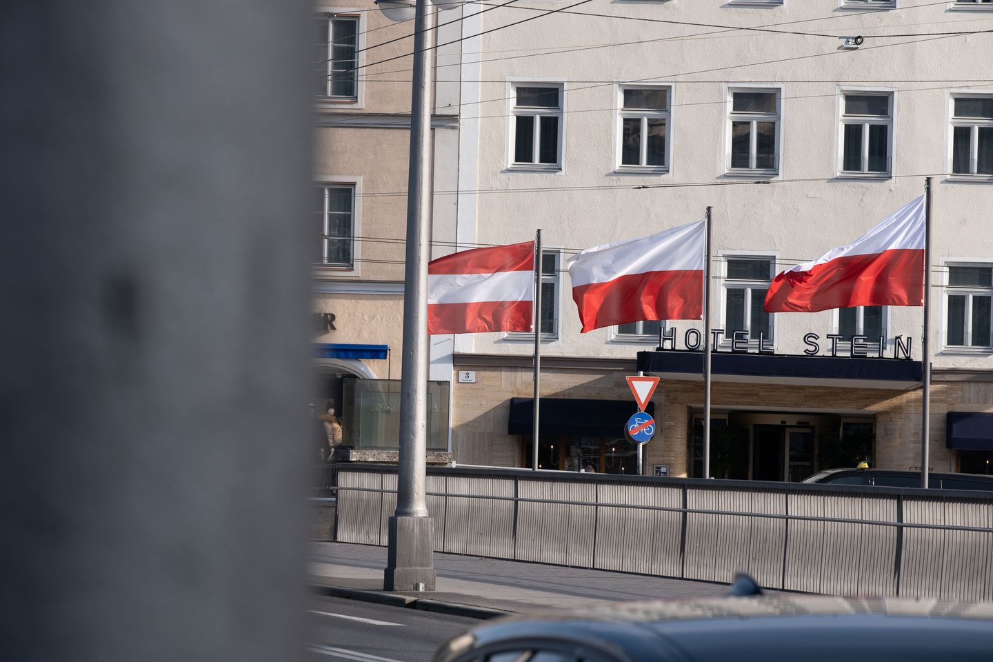 Three flags fly outside the Hotel Stein entrance across the street in Salzburg.