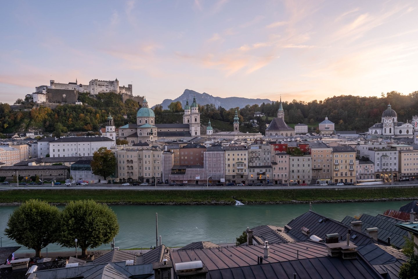Panorama of Hohensalzburg Fortress and Altstadt skyline above the Salzach at sunset in Salzburg.
