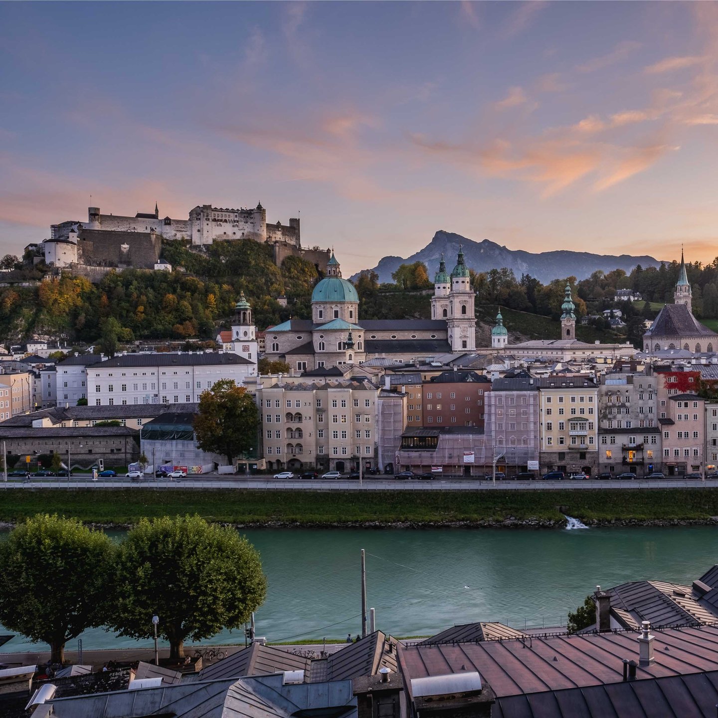 Panorama of Hohensalzburg Fortress and Altstadt skyline above the Salzach at sunset in Salzburg.