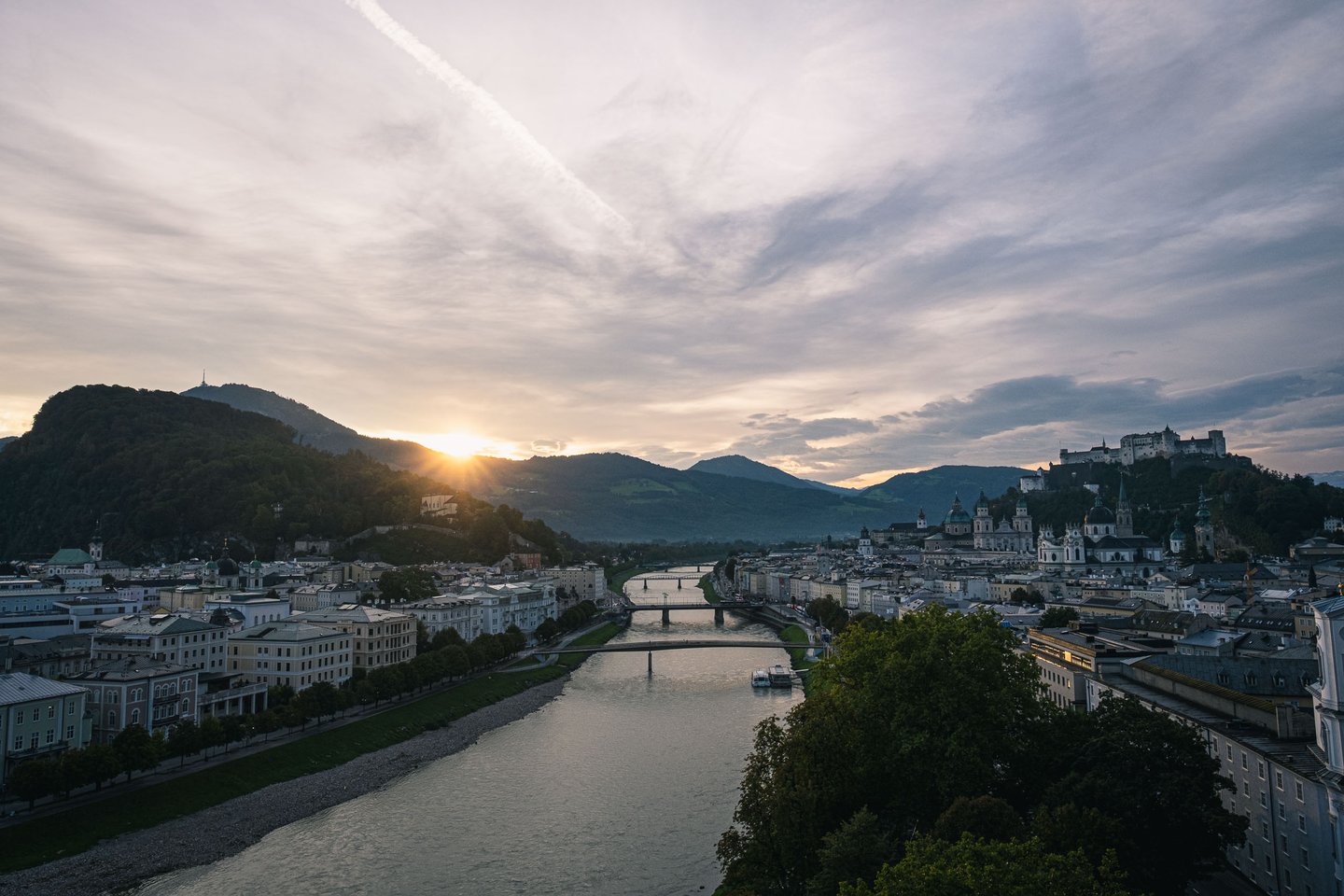 Sun rises over Gaisberg with Salzach River and Altstadt fortress seen from Humboldtterrasse in Salzburg.
