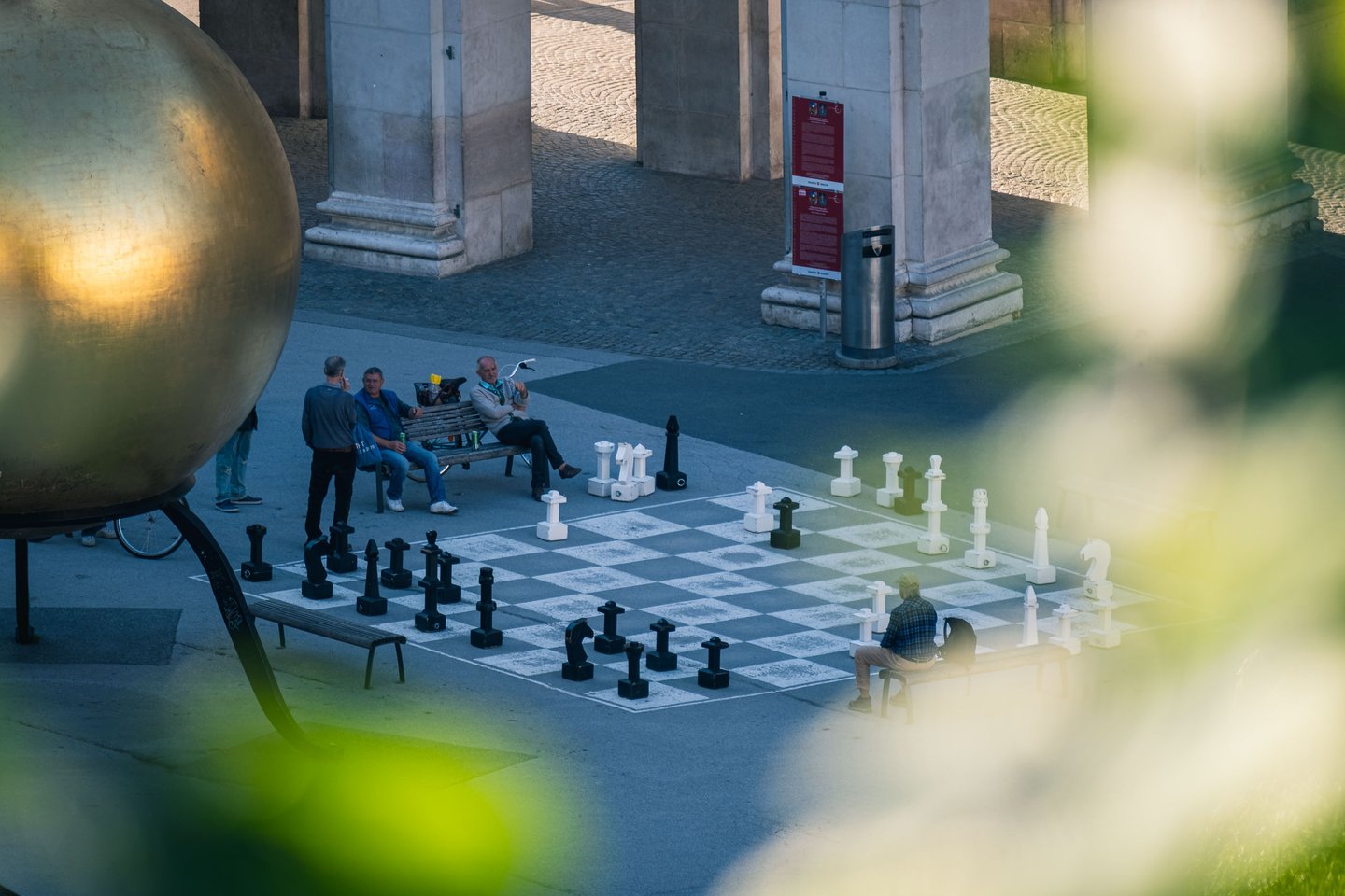 Giant chess board on Kapitelplatz with the golden Sphaera sculpture in the foreground in Salzburg.
