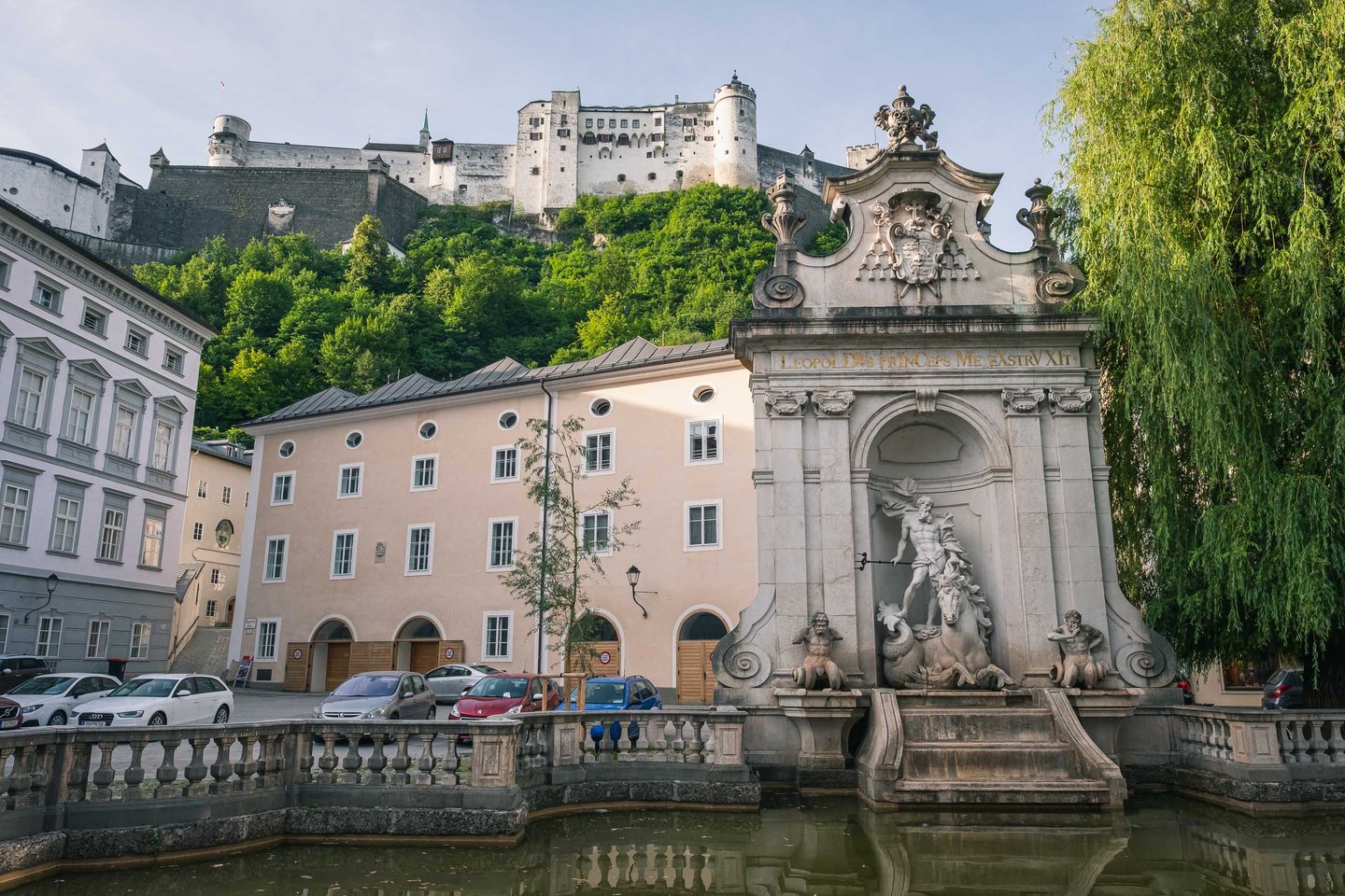 Kapitelschwemme fountain with Triton sculpture below Hohensalzburg fortress in Salzburg old town