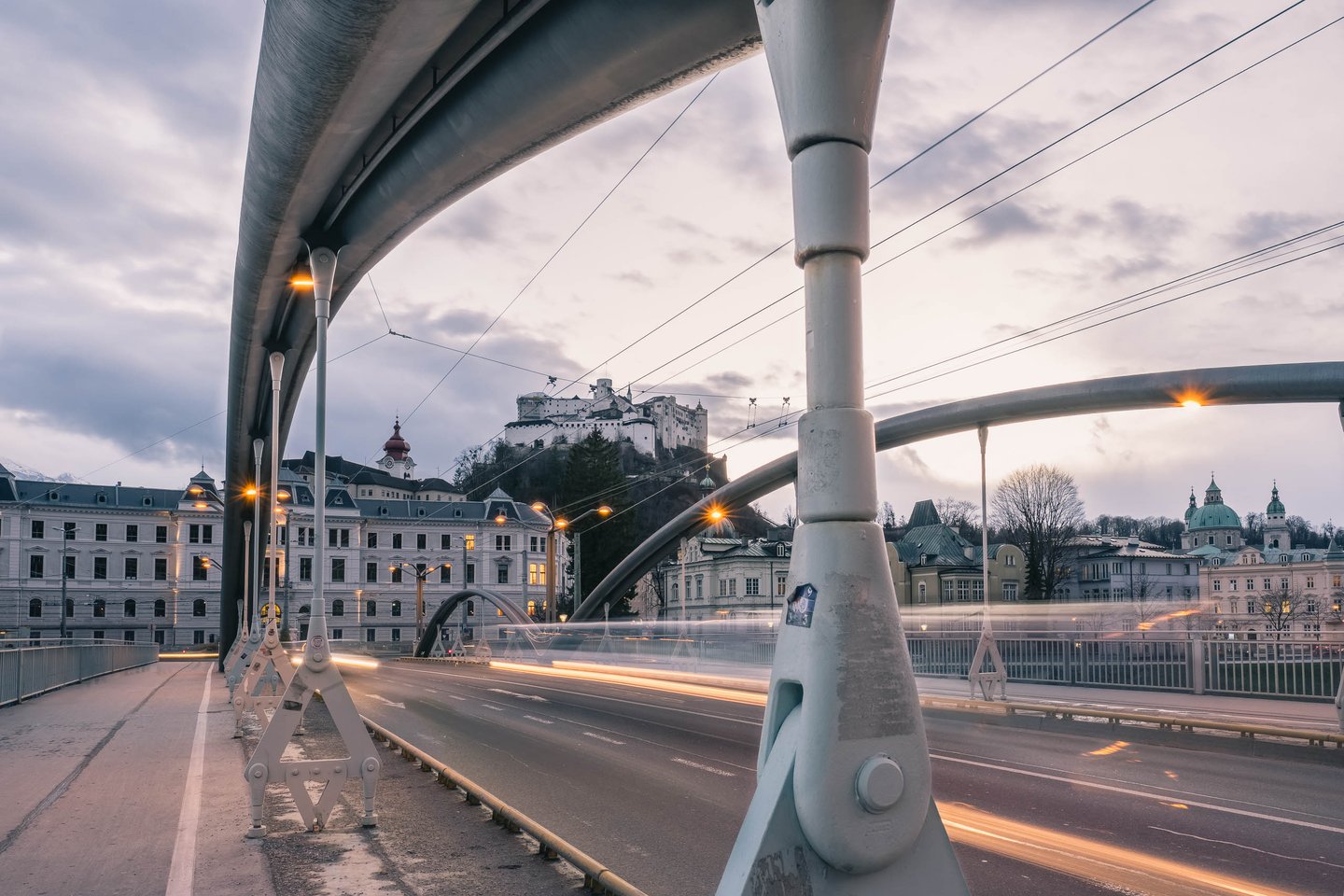 View of the Hohensalzburg Fortress at dusk through the metal-arch structure of the Karolinenbruecke