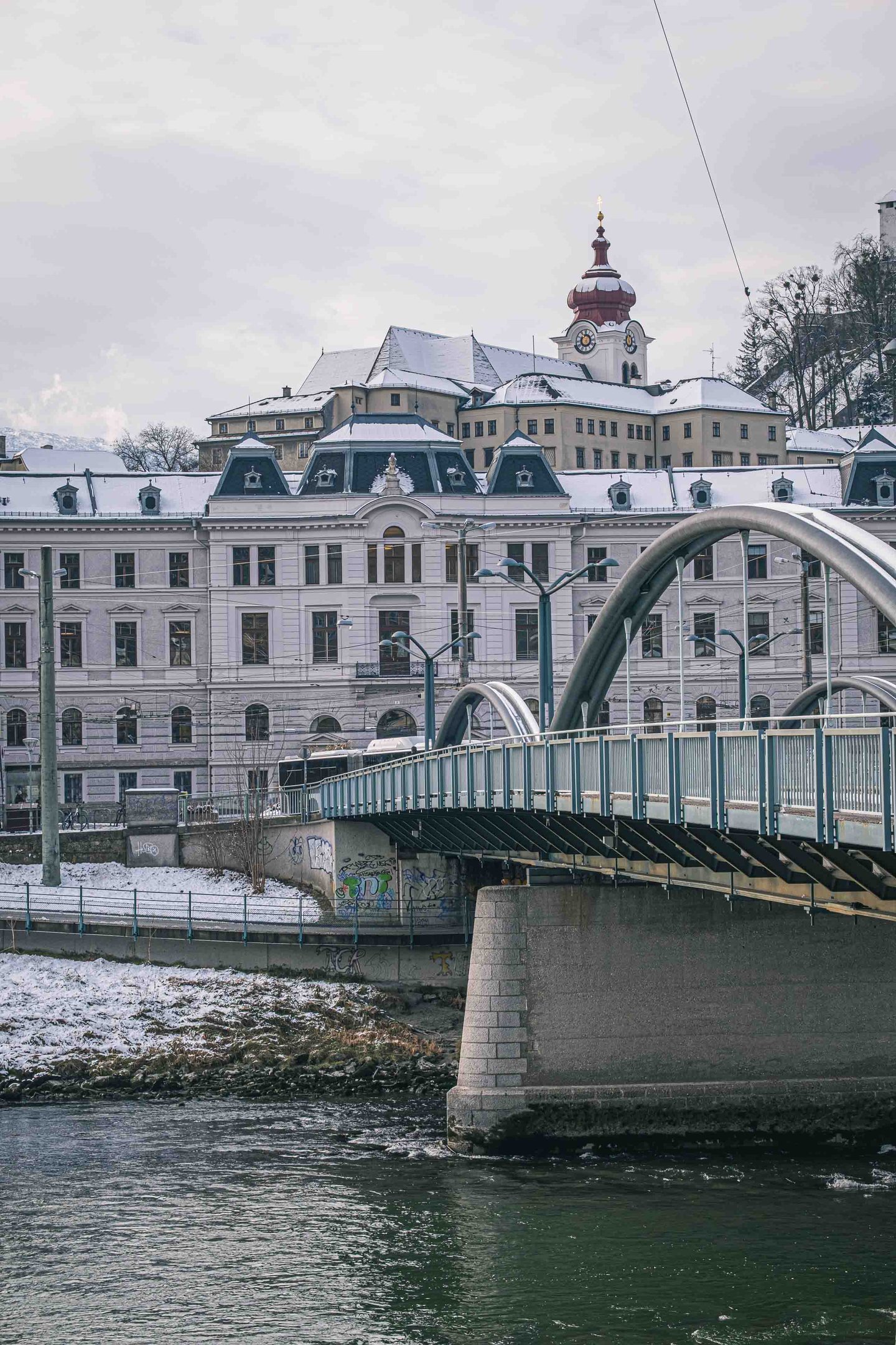 Karolinenbruecke crossing the Salzach with the Salzburg Justizgebaeude on the bank under fresh snow