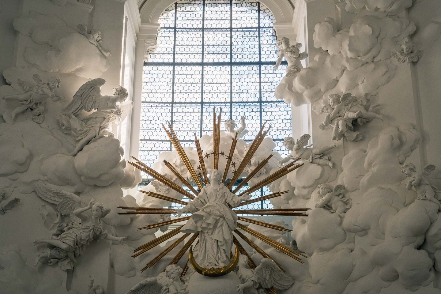 Madonna with golden sunburst and stucco cloud angels behind east window of Kollegienkirche in Salzburg