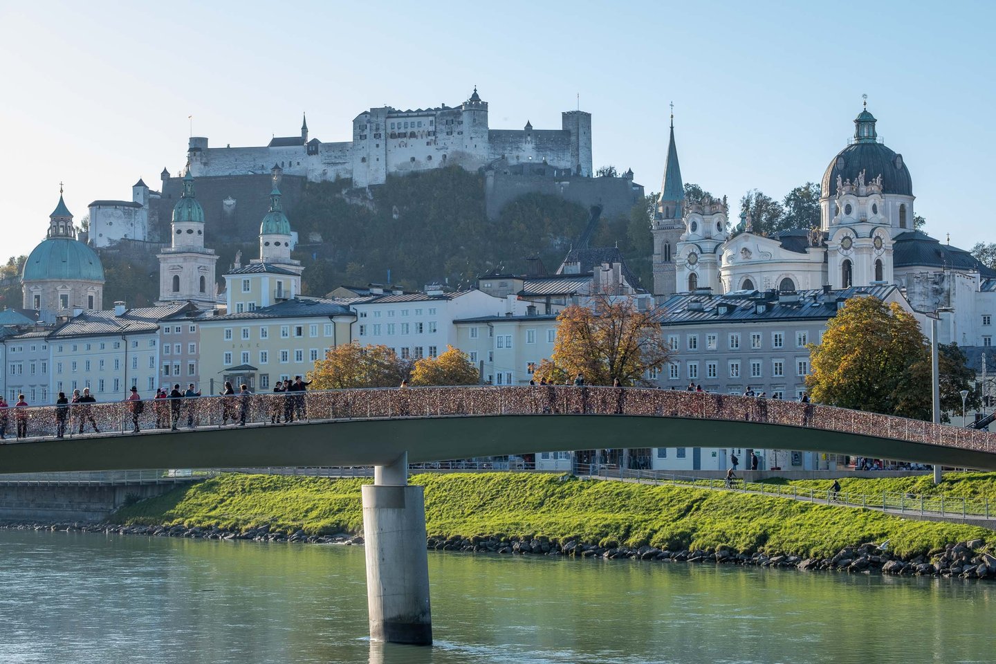 Pedestrian Marko Feingold Steg crosses the Salzach with Hohensalzburg Fortress rising behind in Salzburg.