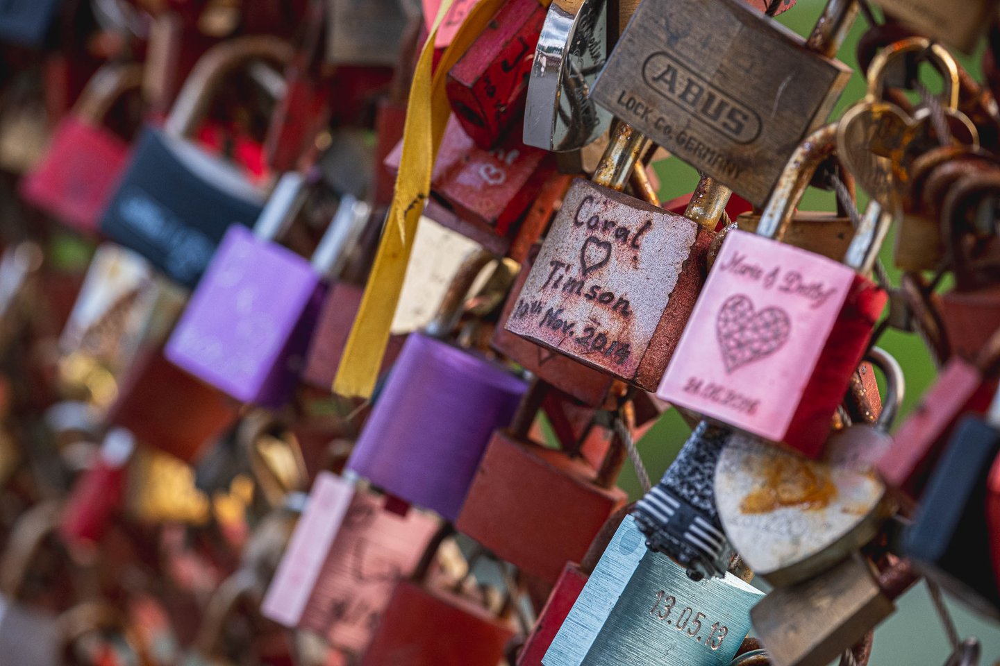 Engraved love padlocks attached to the Marko-Feingold-Steg pedestrian bridge railing in Salzburg.