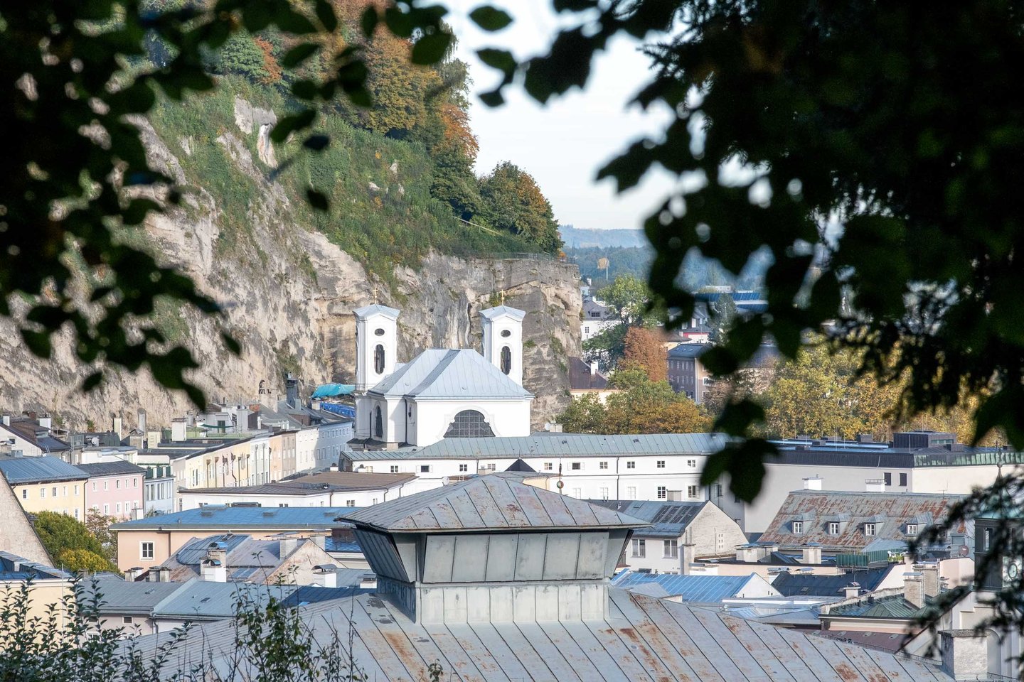 Markuskirche twin towers tucked beneath the Moenchsberg cliff in Salzburg old town.