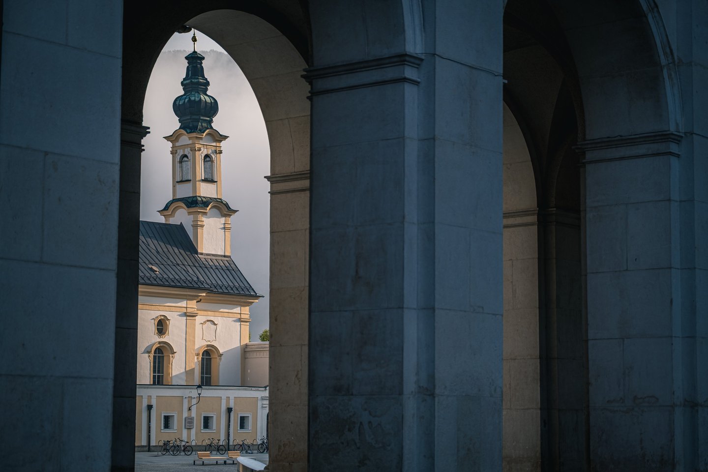 Michaelskirche tower framed through Residenzplatz arcade arches in Salzburg old town