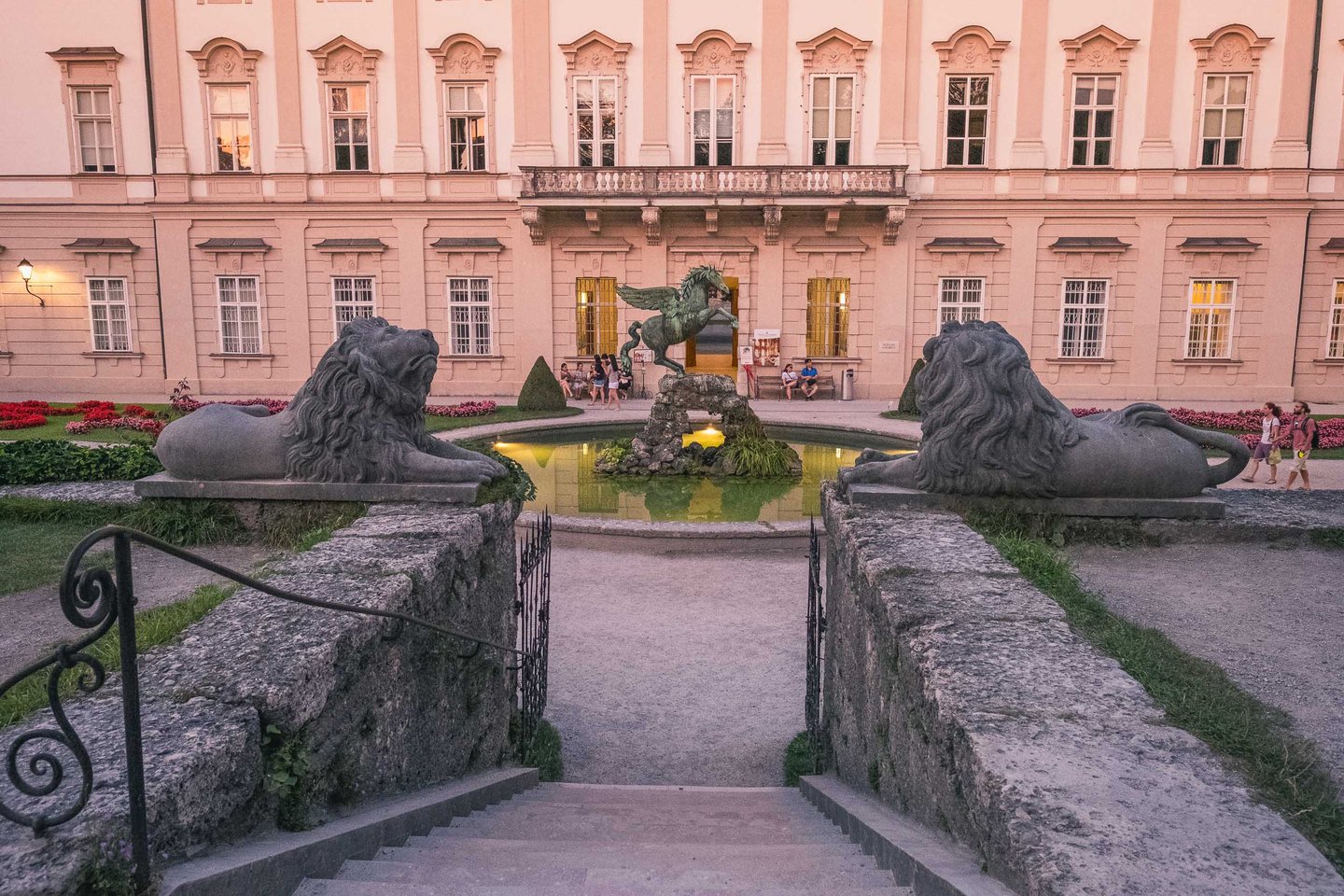 Mirabell Gardens Pegasus fountain on a reflecting pool flanked by stone lion statues with the Mirabell Palace facade behind in evening light in Salzburg