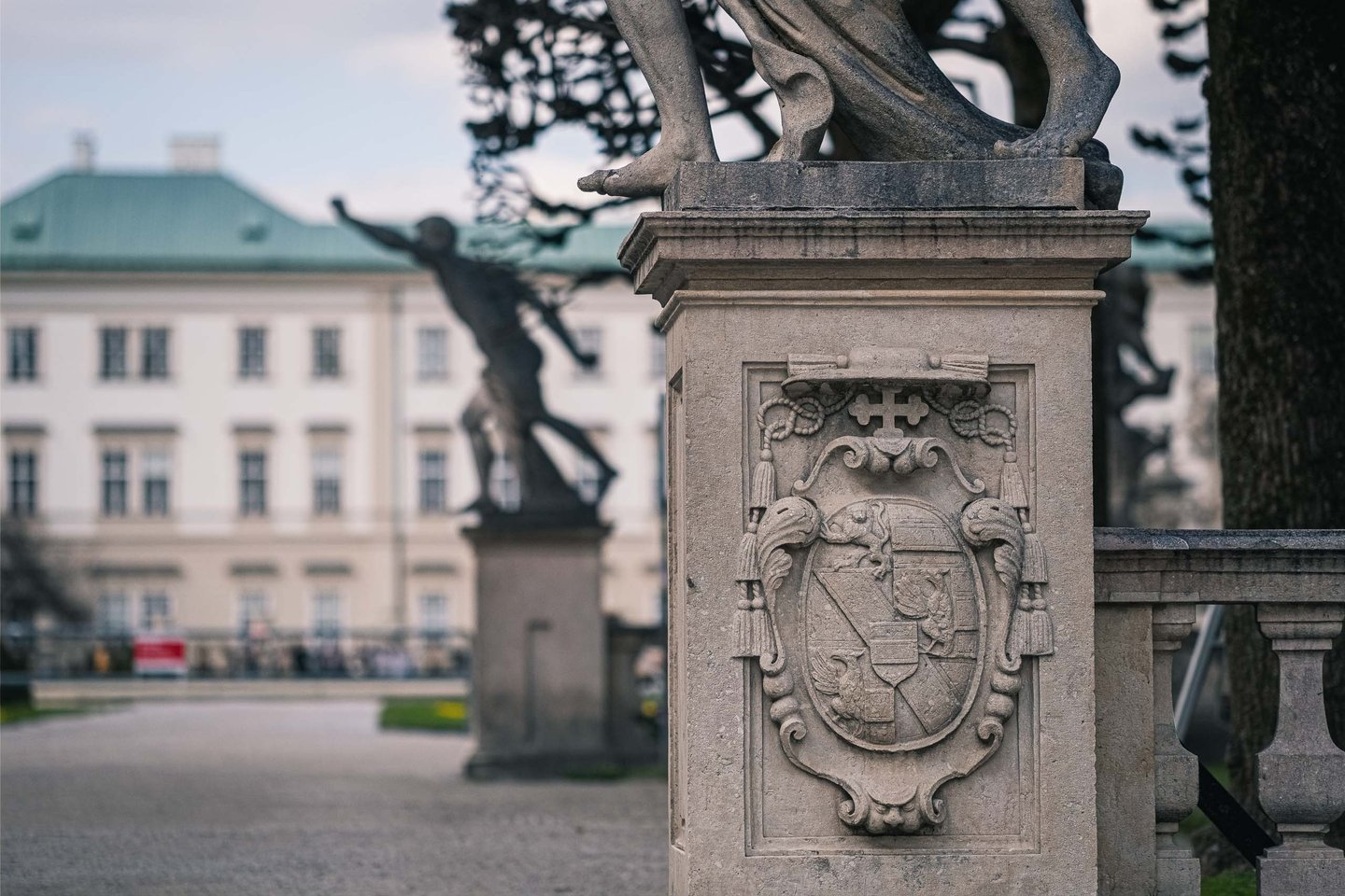 Baroque coat of arms and statue base at the Mirabell Palace garden balustrade in Salzburg.