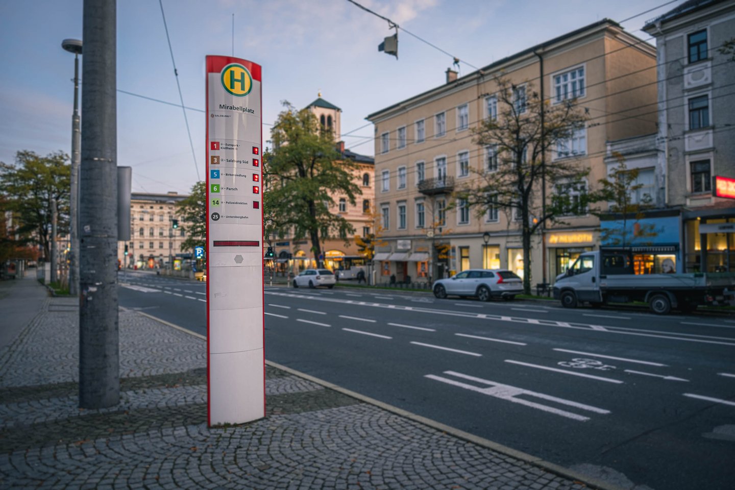 Bus stop sign on Mirabellplatz square with Markuskirche tower visible behind in Salzburg.