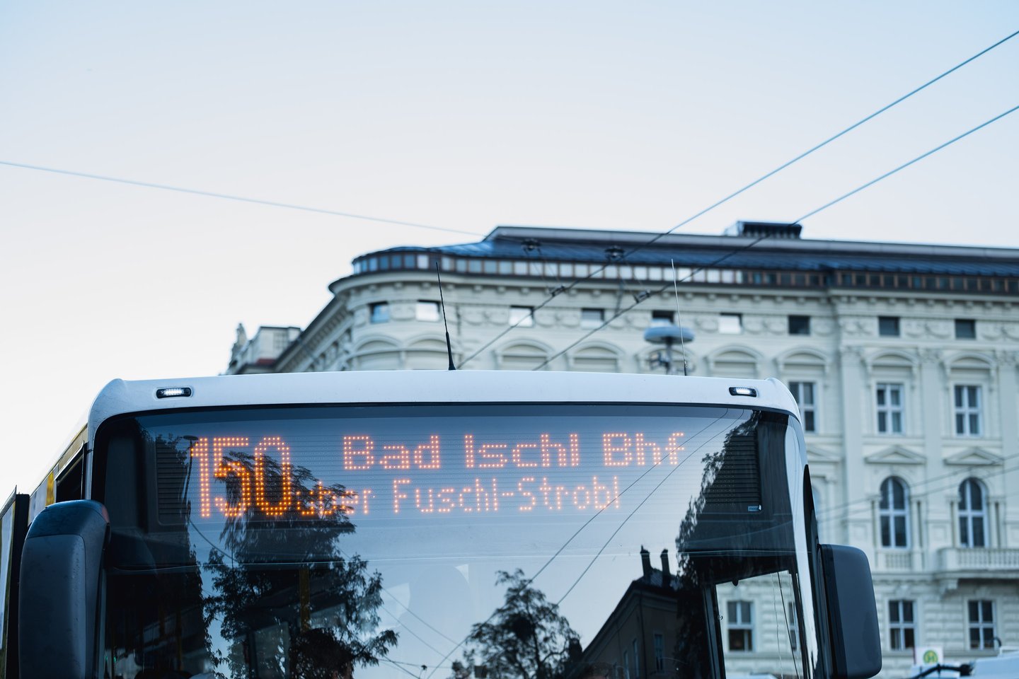 Postbus destination display reading Bad Ischl in front of the Mozarteum facade at Mirabellplatz in Salzburg.