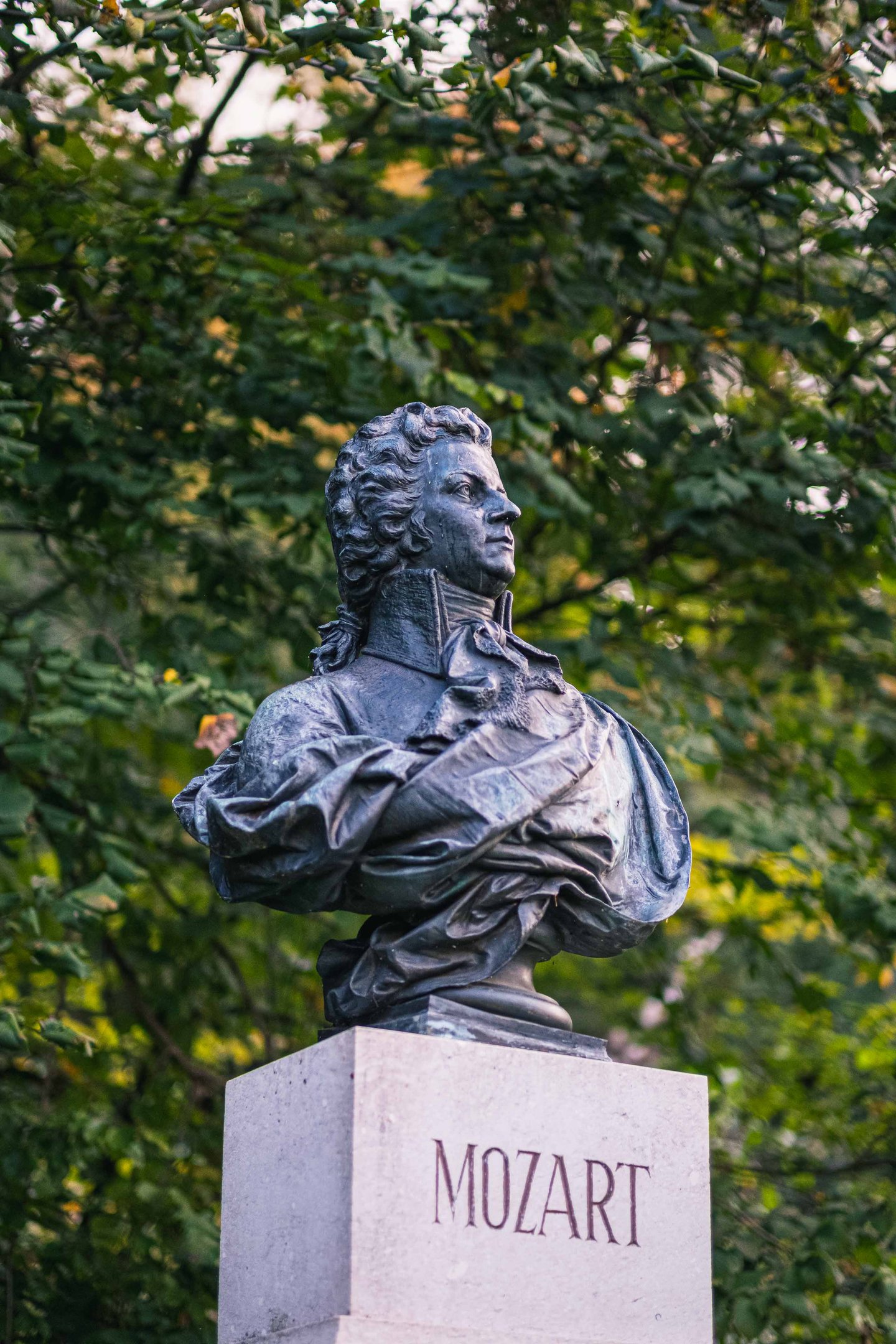 Bronze Mozart bust with MOZART pedestal label in a wooded clearing on Kapuzinerberg in Salzburg.