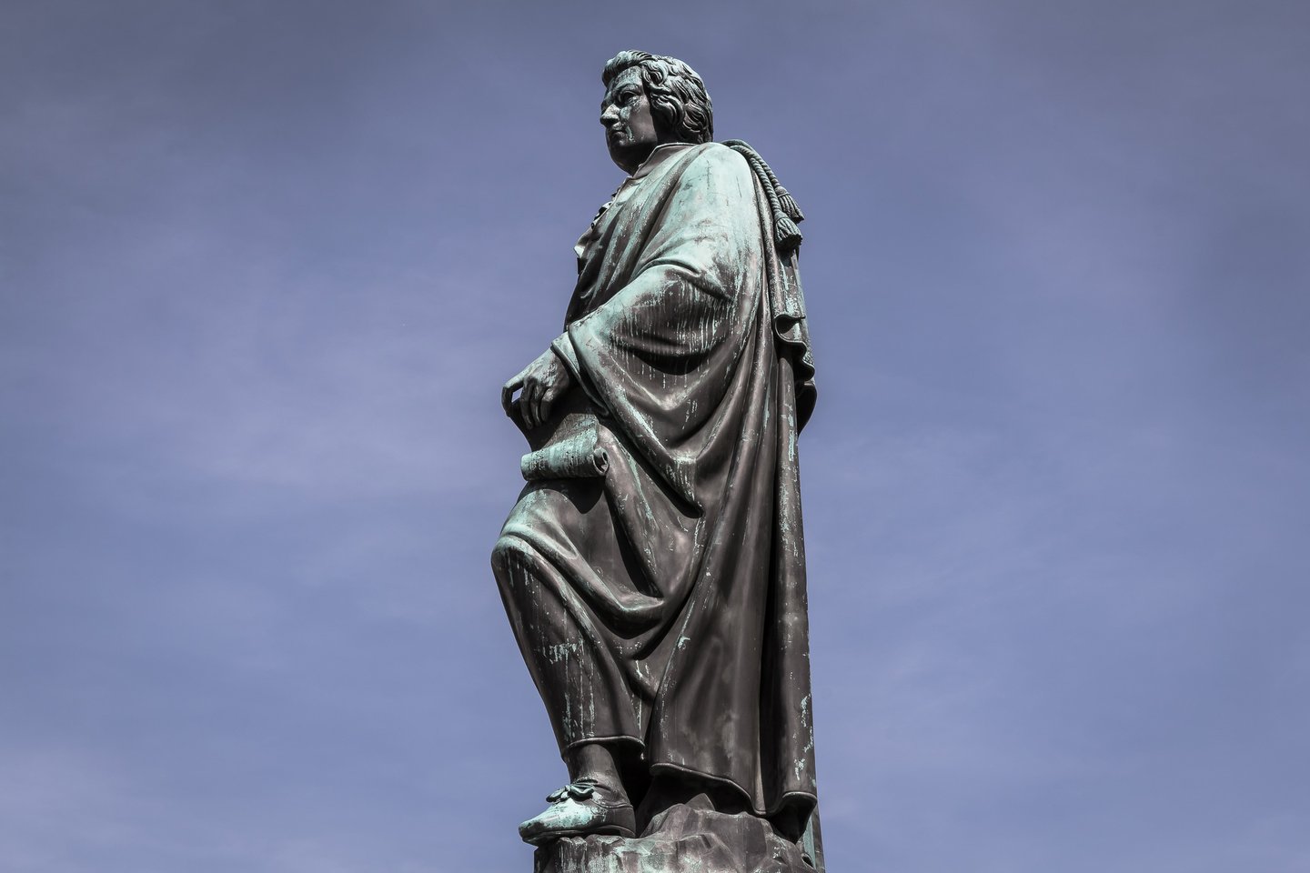 Bronze Mozart statue silhouetted against a pale blue sky on Mozartplatz in Salzburg old town