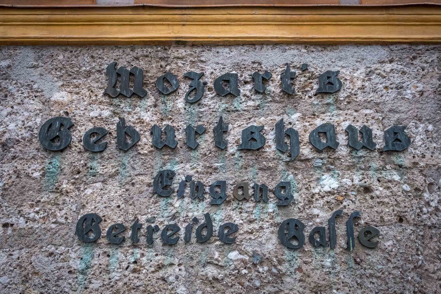 Close-up of the Mozarts Geburtshaus Eingang Getreide Gasse lettering on a weathered stone wall in Salzburg