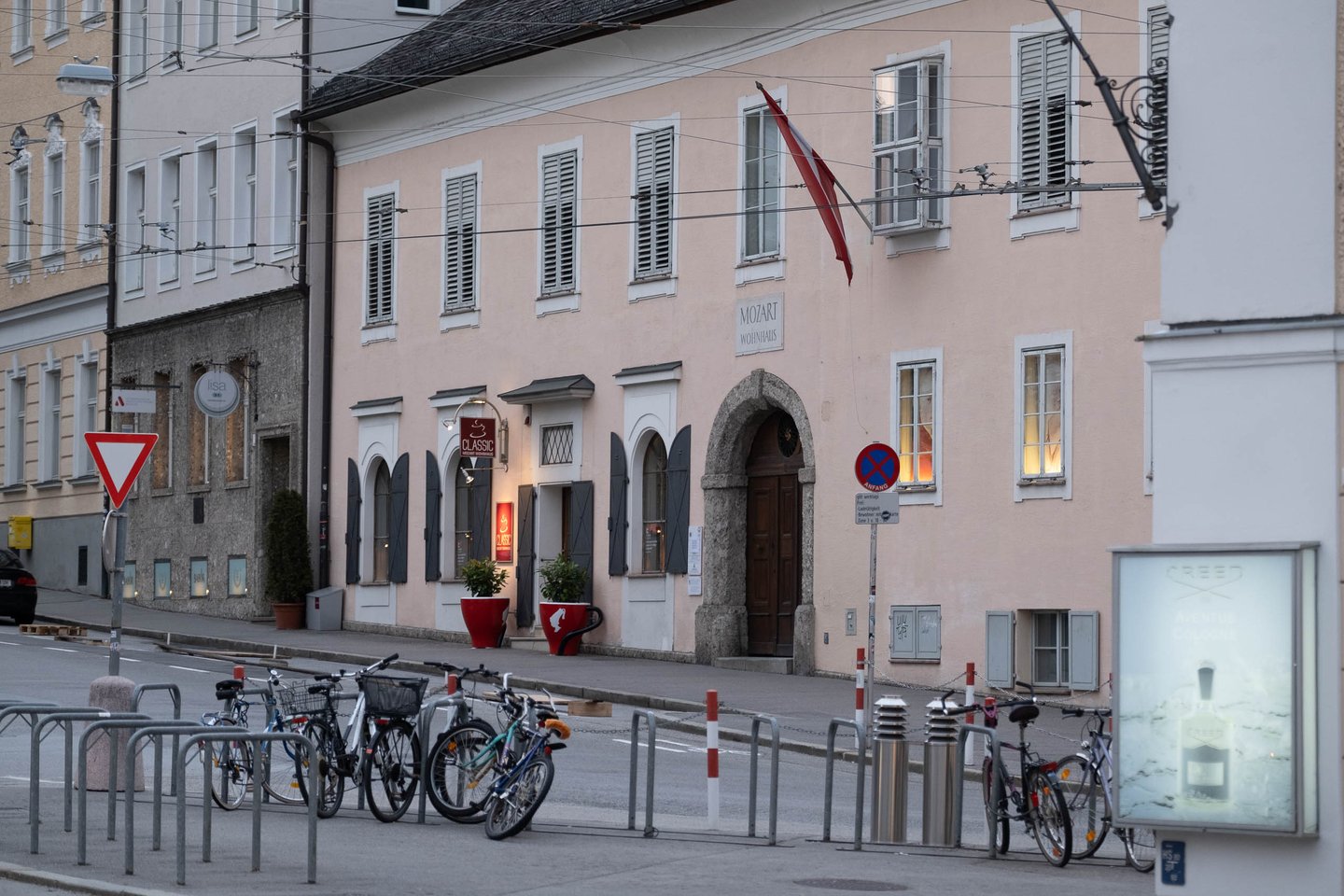 Exterior of Mozart's Residence on Makartplatz at dusk with cafe chairs outside in Salzburg.